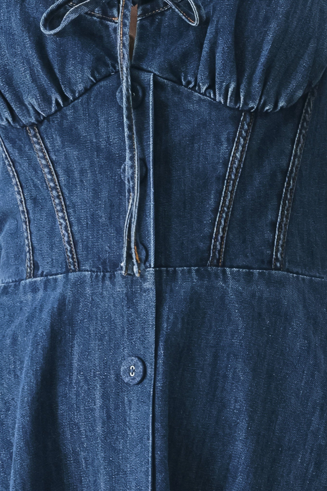 Close up of an indigo blue denim midi dress featuring sweetheart neckline with tie, straps, corset waist, front button detail, circle skirt and back zipper closure | FREEMARKET
