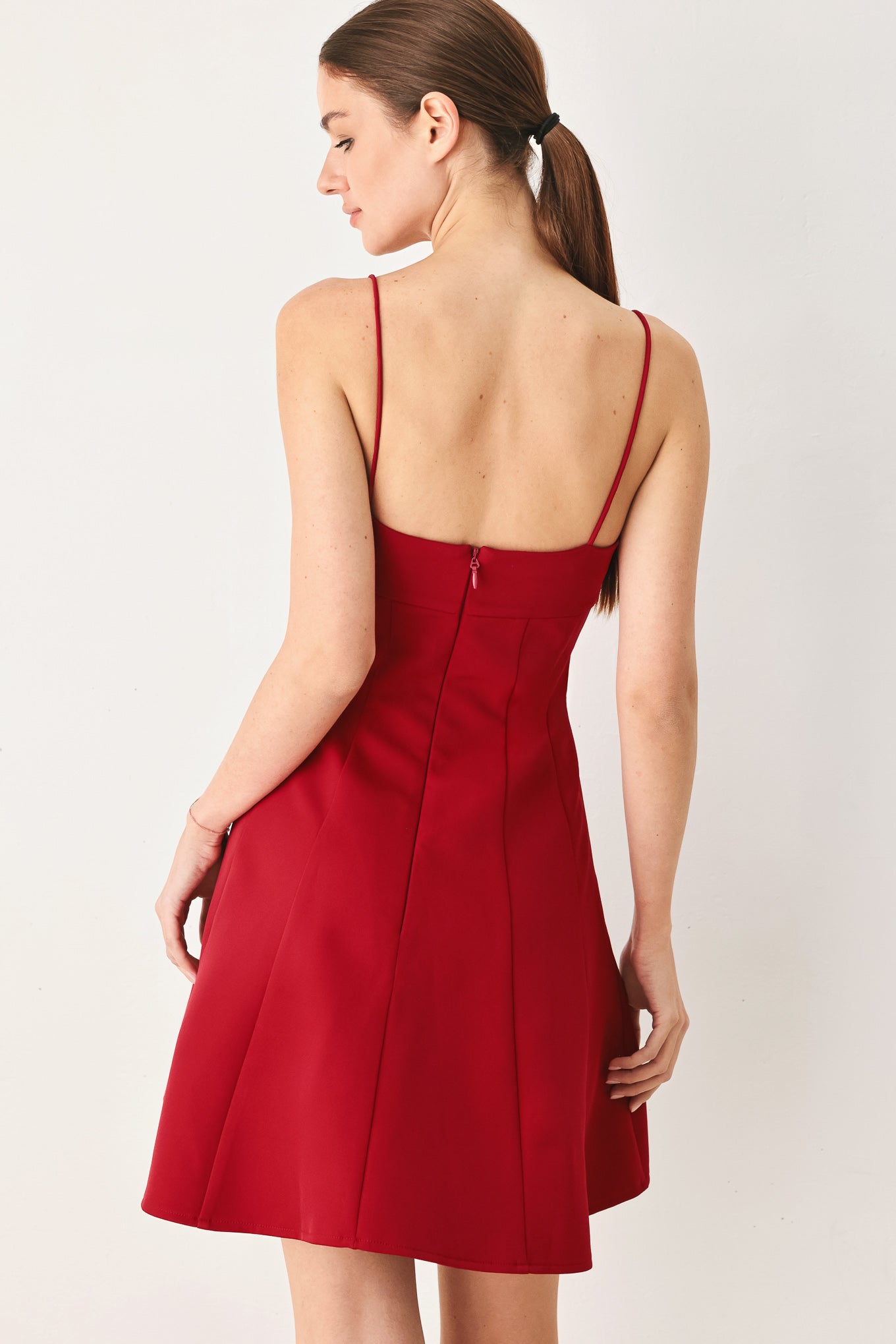 A woman wearing a red spaghetti-strap mini dress with a structured bodice and flared skirt | Flying Tomato