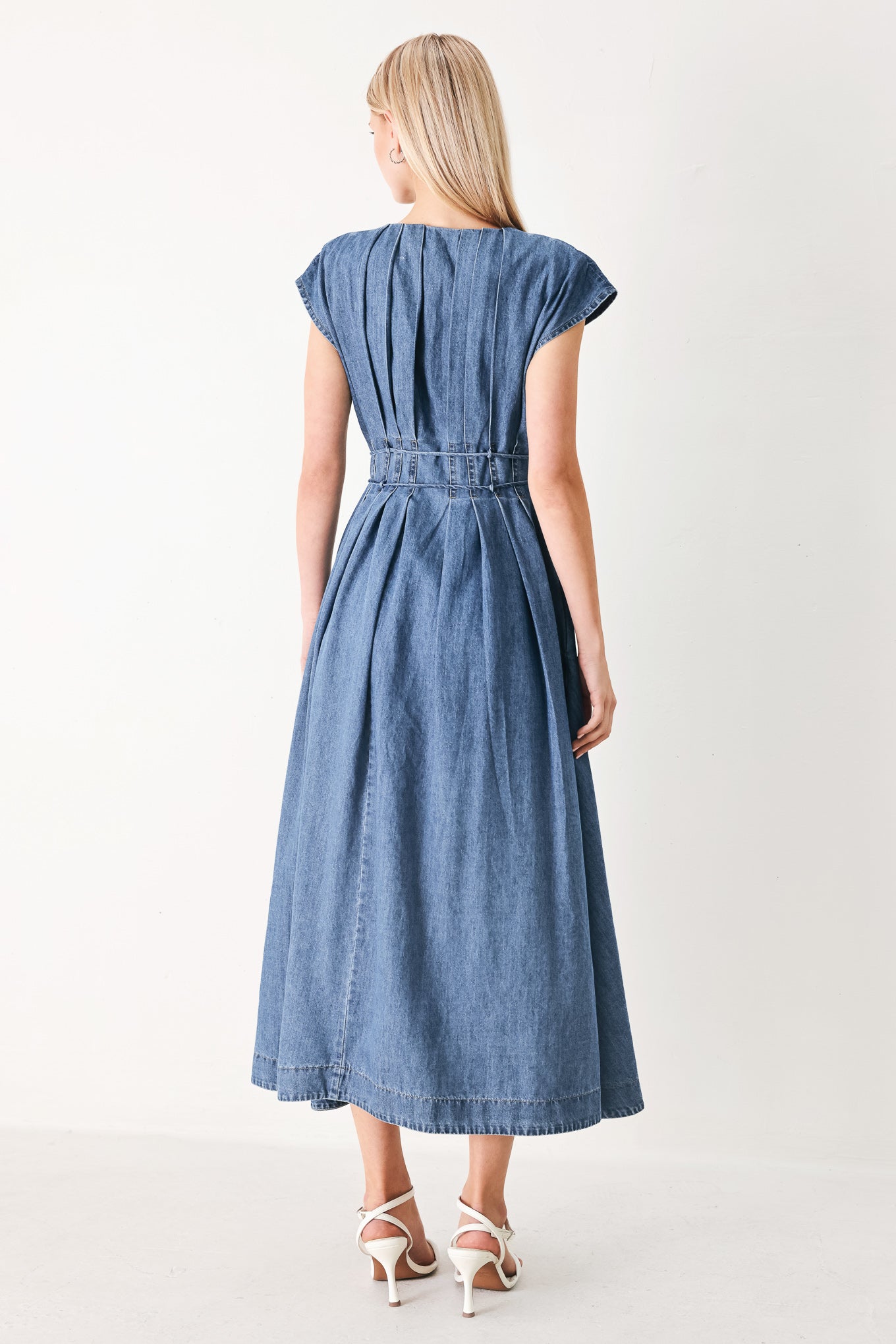 Woman wearing a blue denim midi dress featuring V neckline, drop shoulder, corset waist with pleats, double tie and full skirt | FREEMARKET