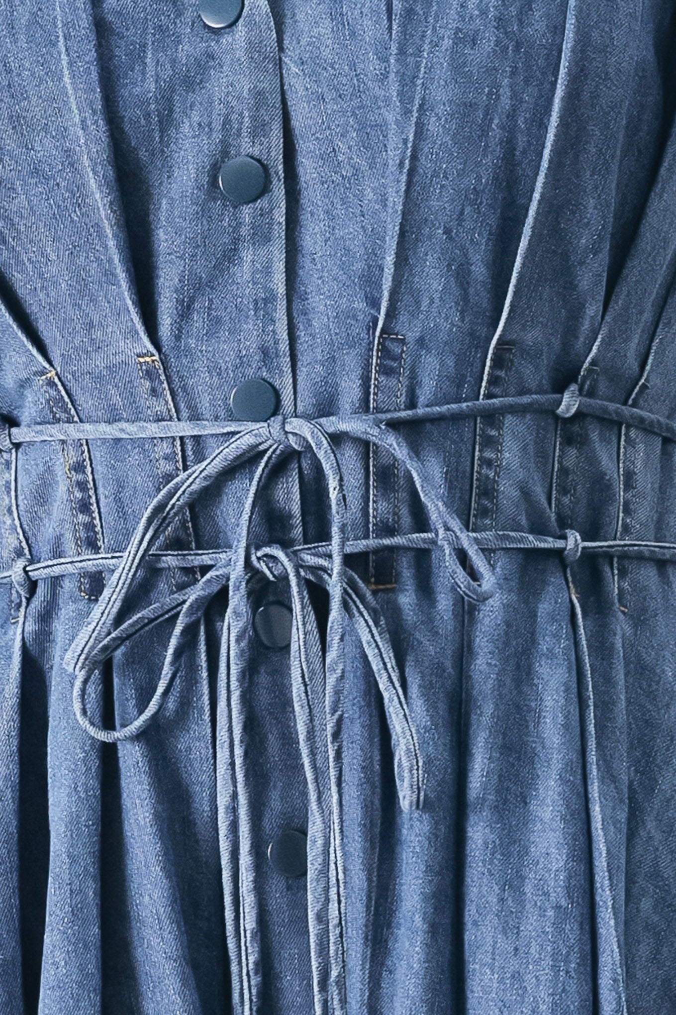 Close up of a blue denim midi dress featuring V neckline, drop shoulder, corset waist with pleats, double tie and full skirt | FREEMARKET