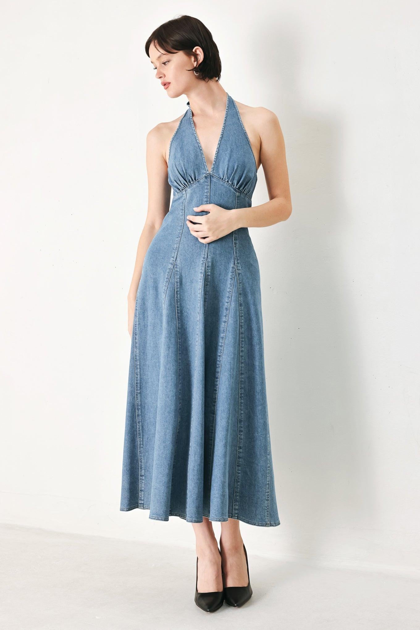 A washed denim midi dress featuring halter neckline with back tie, full circle skirt, bare back with zipper closure