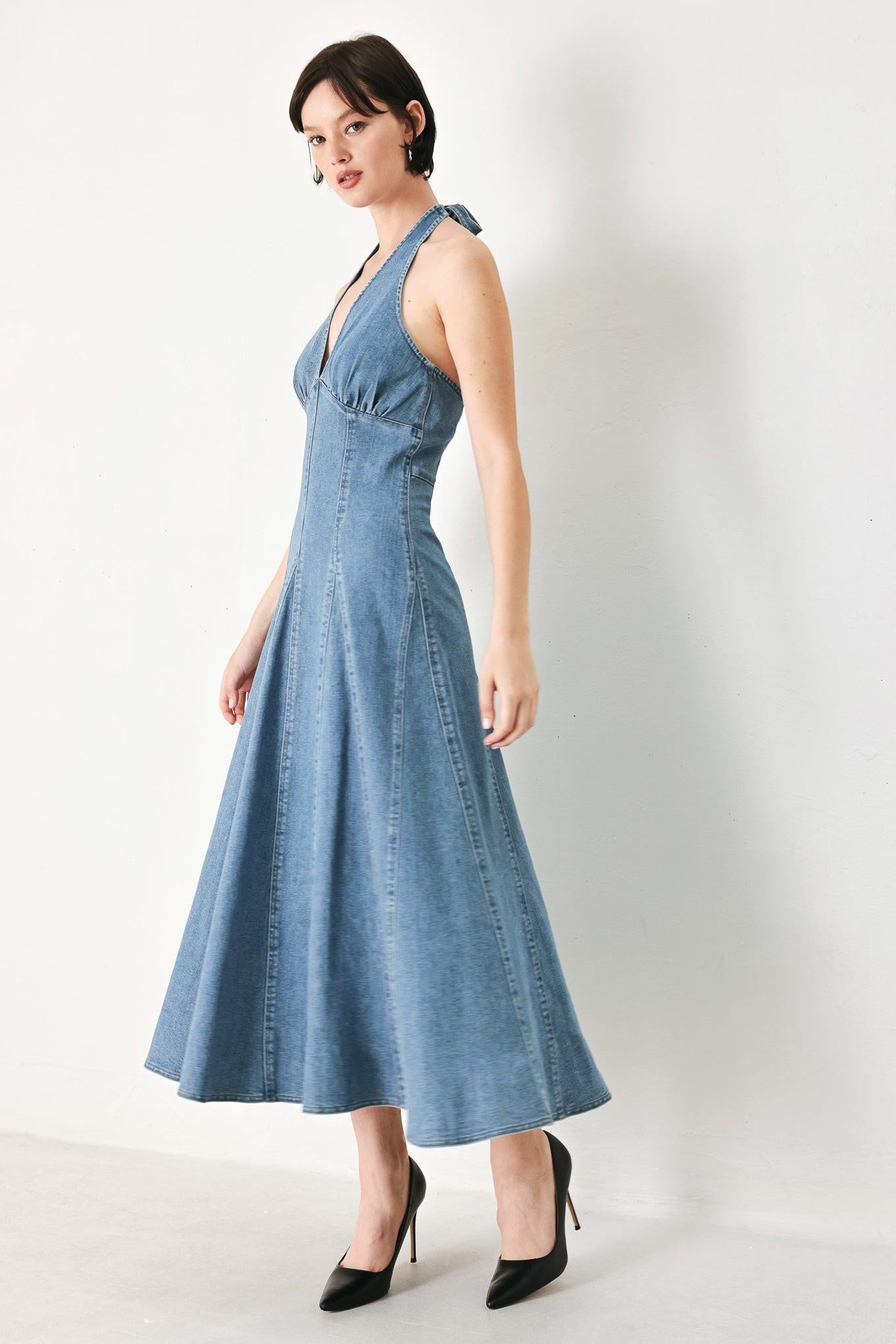 A washed denim midi dress featuring halter neckline with back tie, full circle skirt, bare back with zipper closure