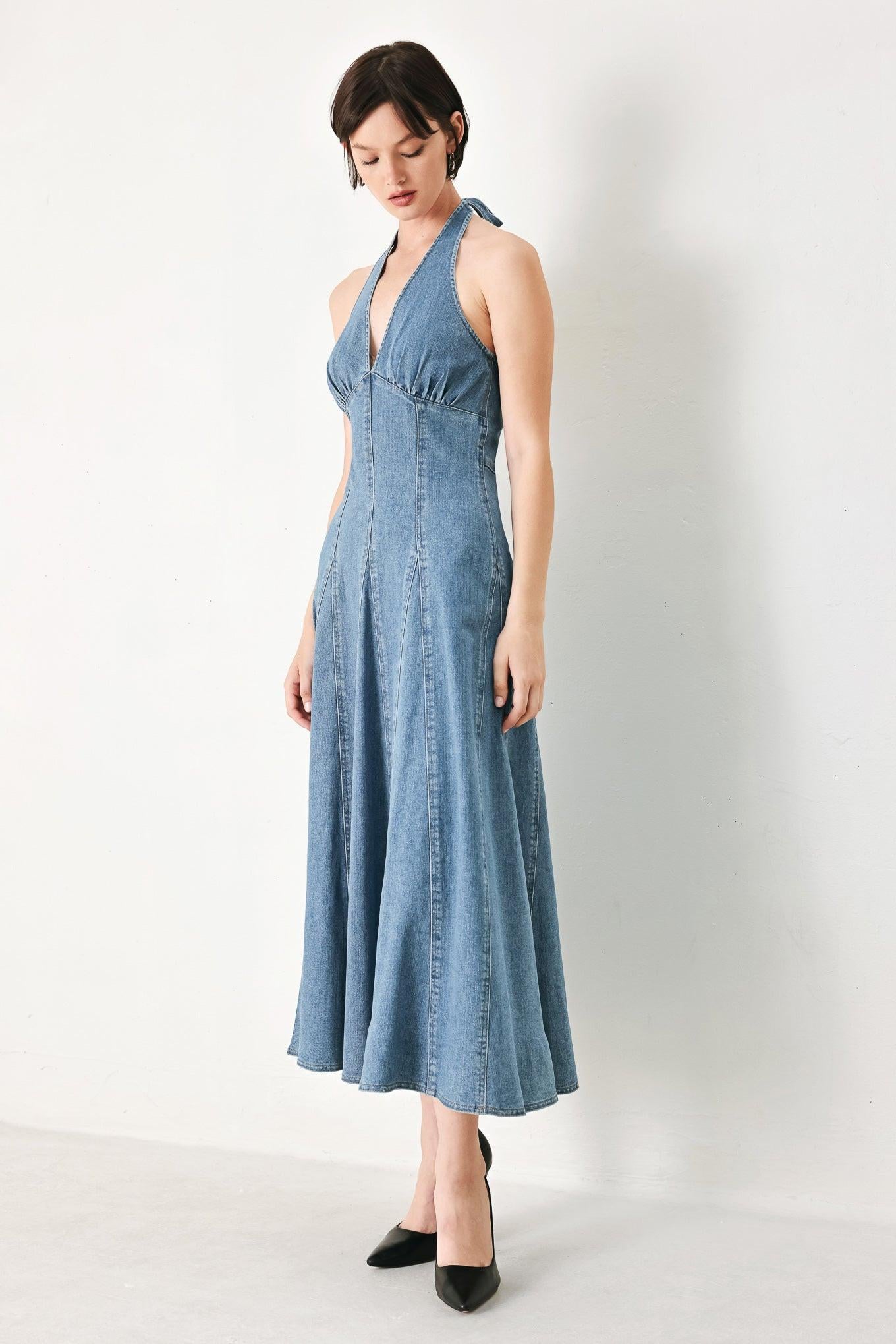 A washed denim midi dress featuring halter neckline with back tie, full circle skirt, bare back with zipper closure