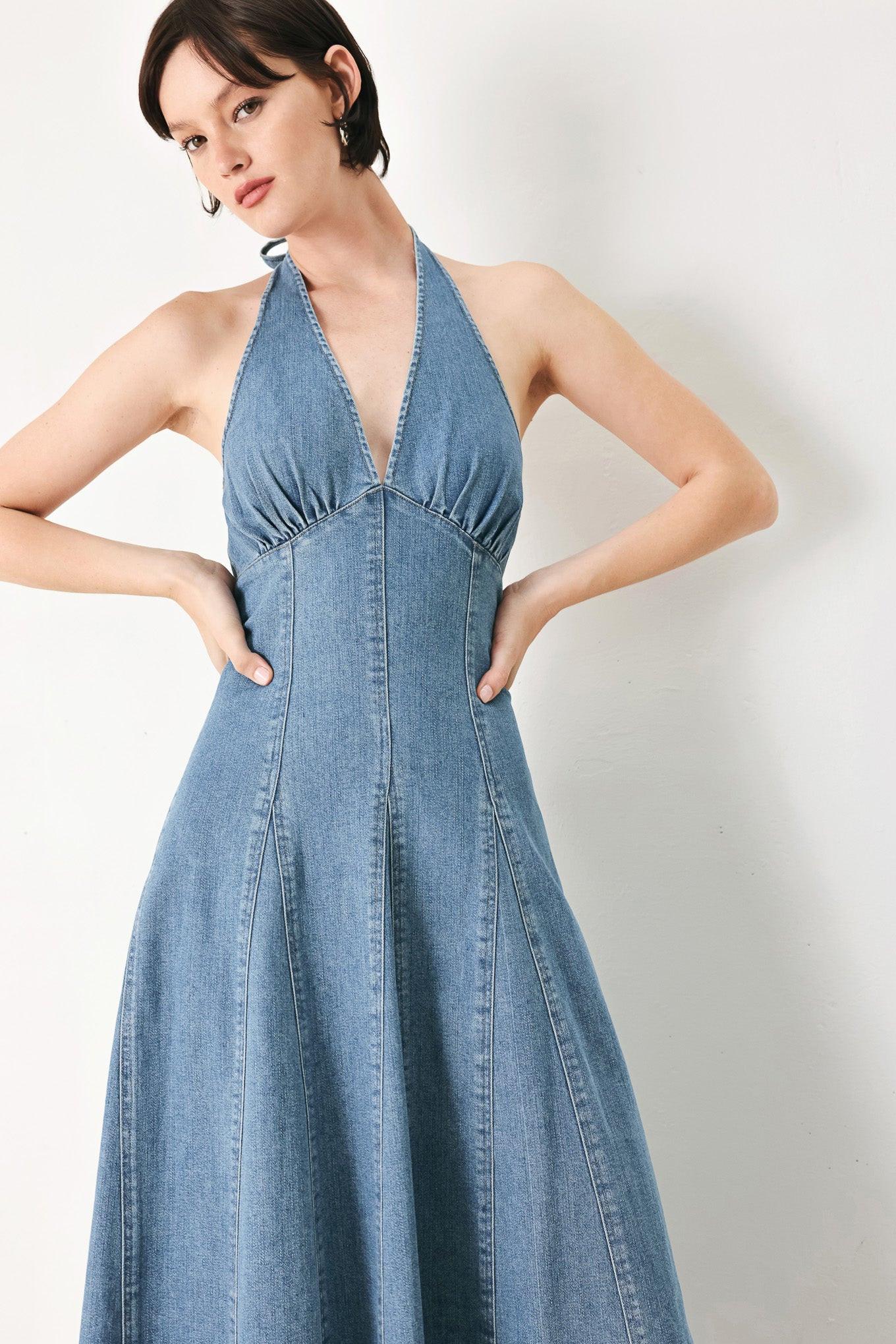 A washed denim midi dress featuring halter neckline with back tie, full circle skirt, bare back with zipper closure
