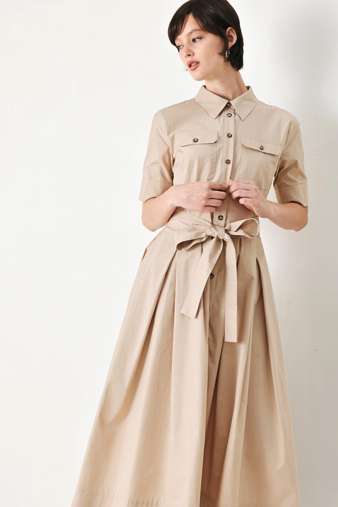 A solid neutral woven midi shirt dress with short sleeve, pockets, self tie and front closure