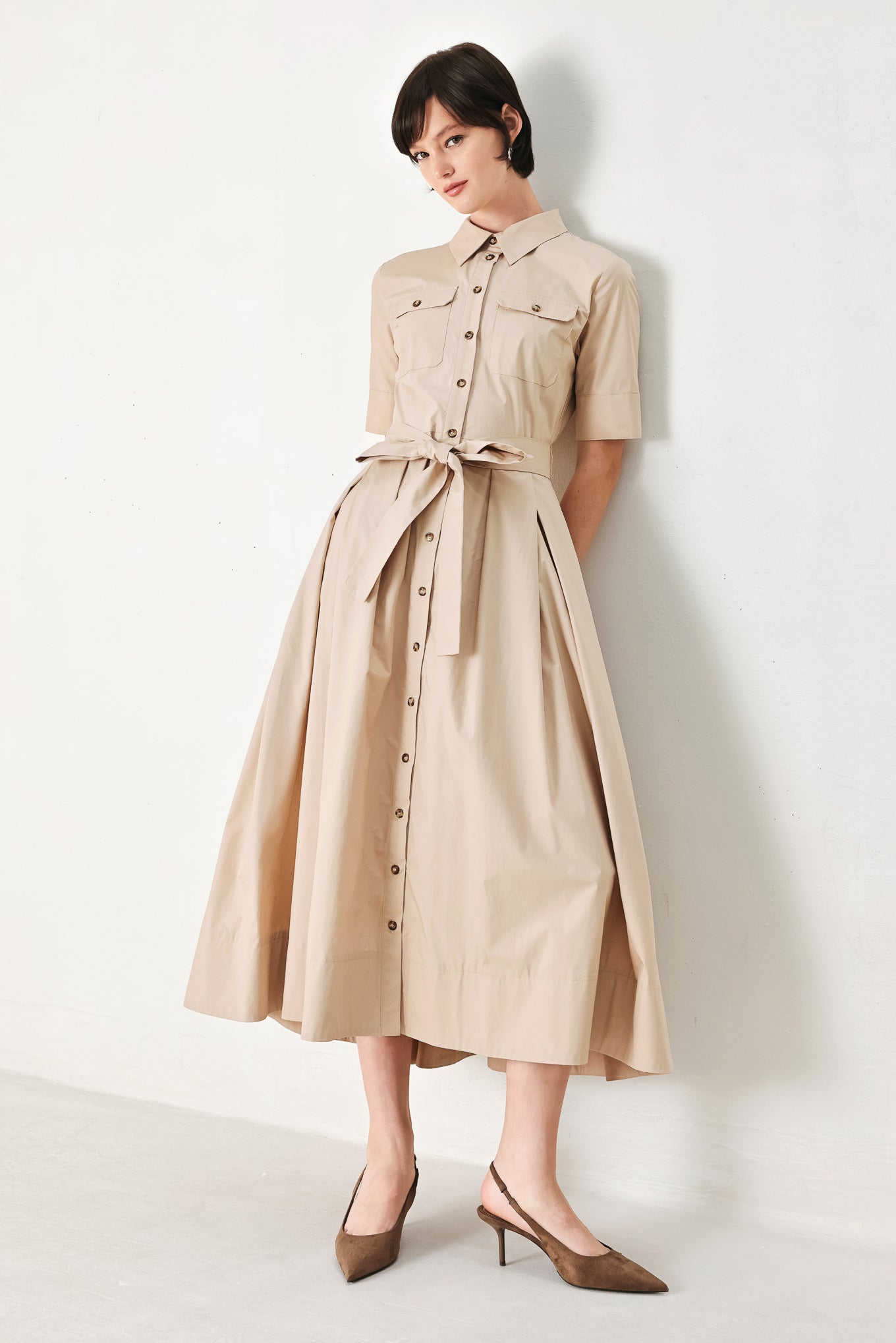 A solid neutral woven midi shirt dress with short sleeve, pockets, self tie and front closure