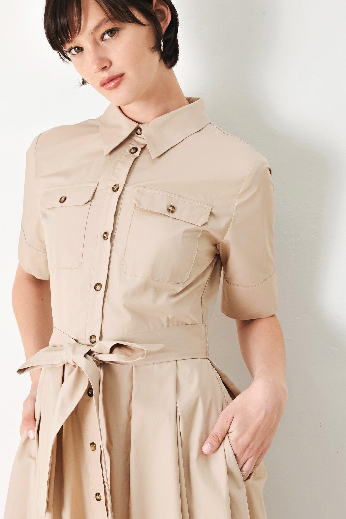 A solid neutral woven midi shirt dress with short sleeve, pockets, self tie and front closure