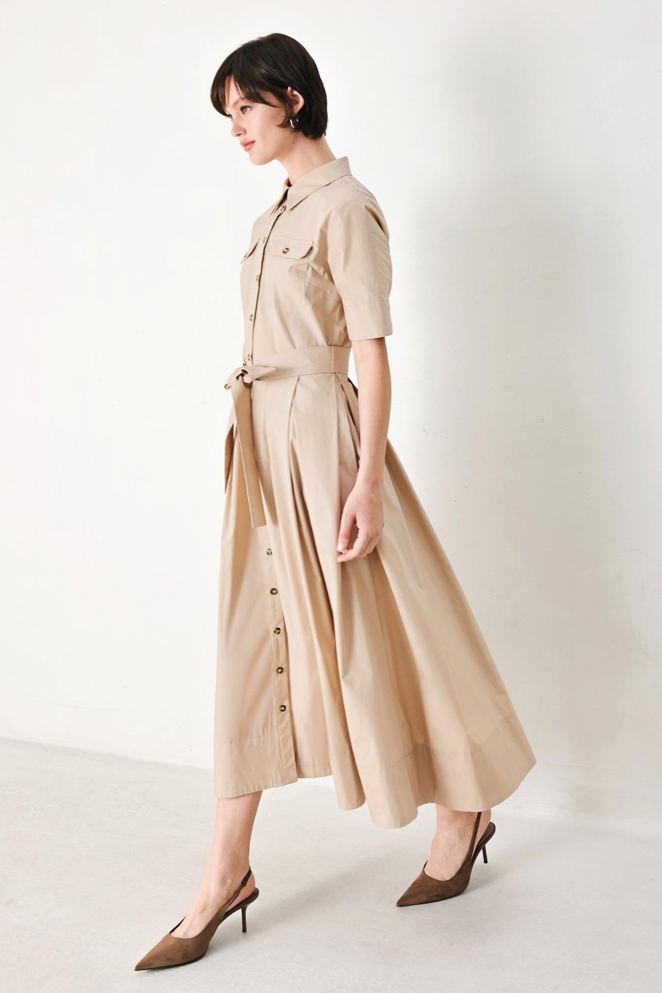 A solid neutral woven midi shirt dress with short sleeve, pockets, self tie and front closure