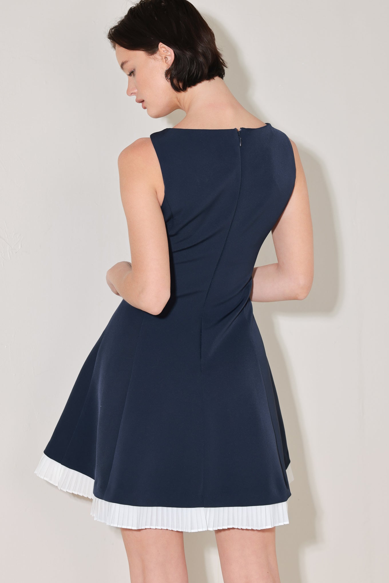 
A solid woven mini dress featuring V neckline, sleeveless, circle skirt with contrasting pleated hem and back zipper closure

Details:

Self : 95% Polyester 5% Spandex
Contrast : 100% Polyester

Size &amp; Fit

- Model is 5`8" And Wearing Size Small
- Measurements Taken From Size Small
- Approx. Length: 34"