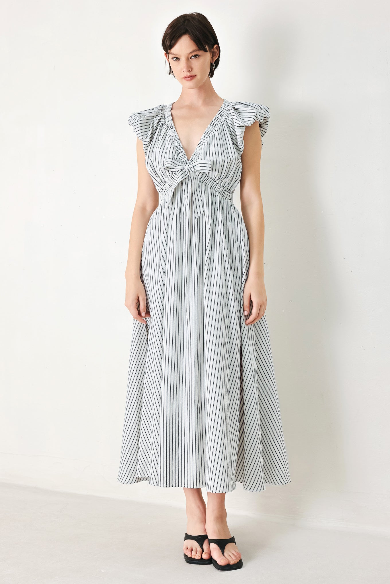 A striped woven midi dress featuring V neckline, short balloon sleeves, front tie, elastic at empire and full skirt