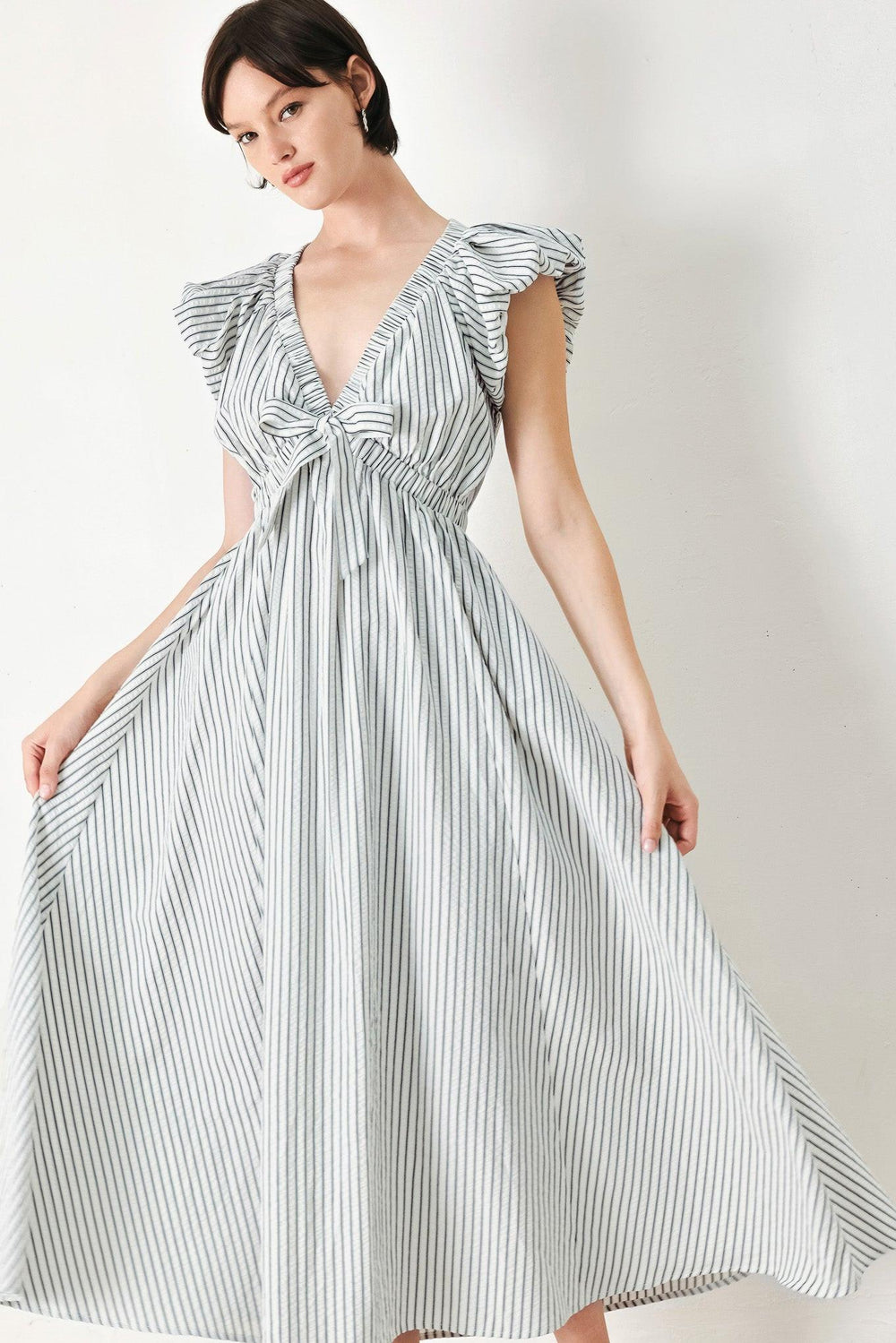A striped woven midi dress featuring V neckline, short balloon sleeves, front tie, elastic at empire and full skirt
