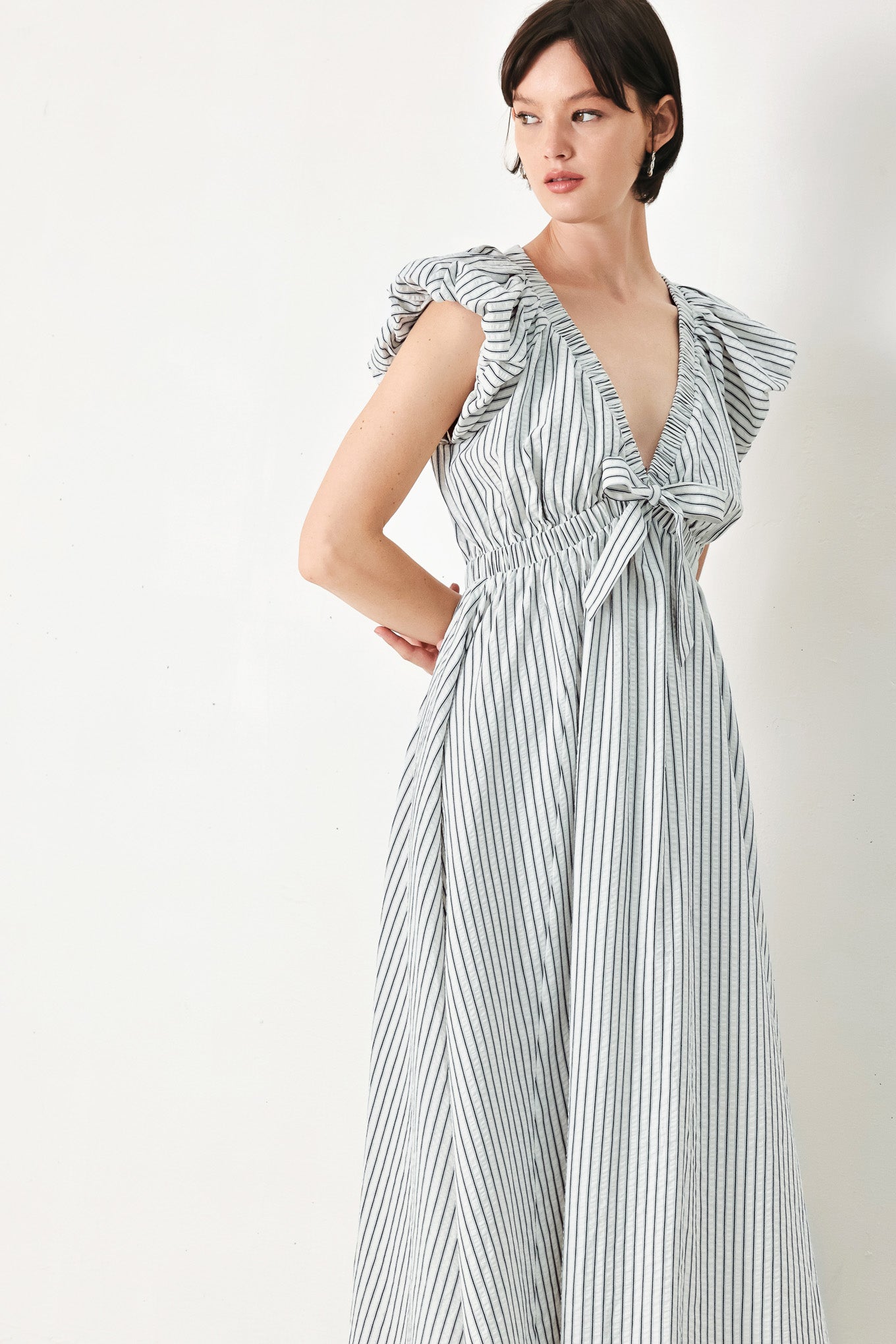 A striped woven midi dress featuring V neckline, short balloon sleeves, front tie, elastic at empire and full skirt