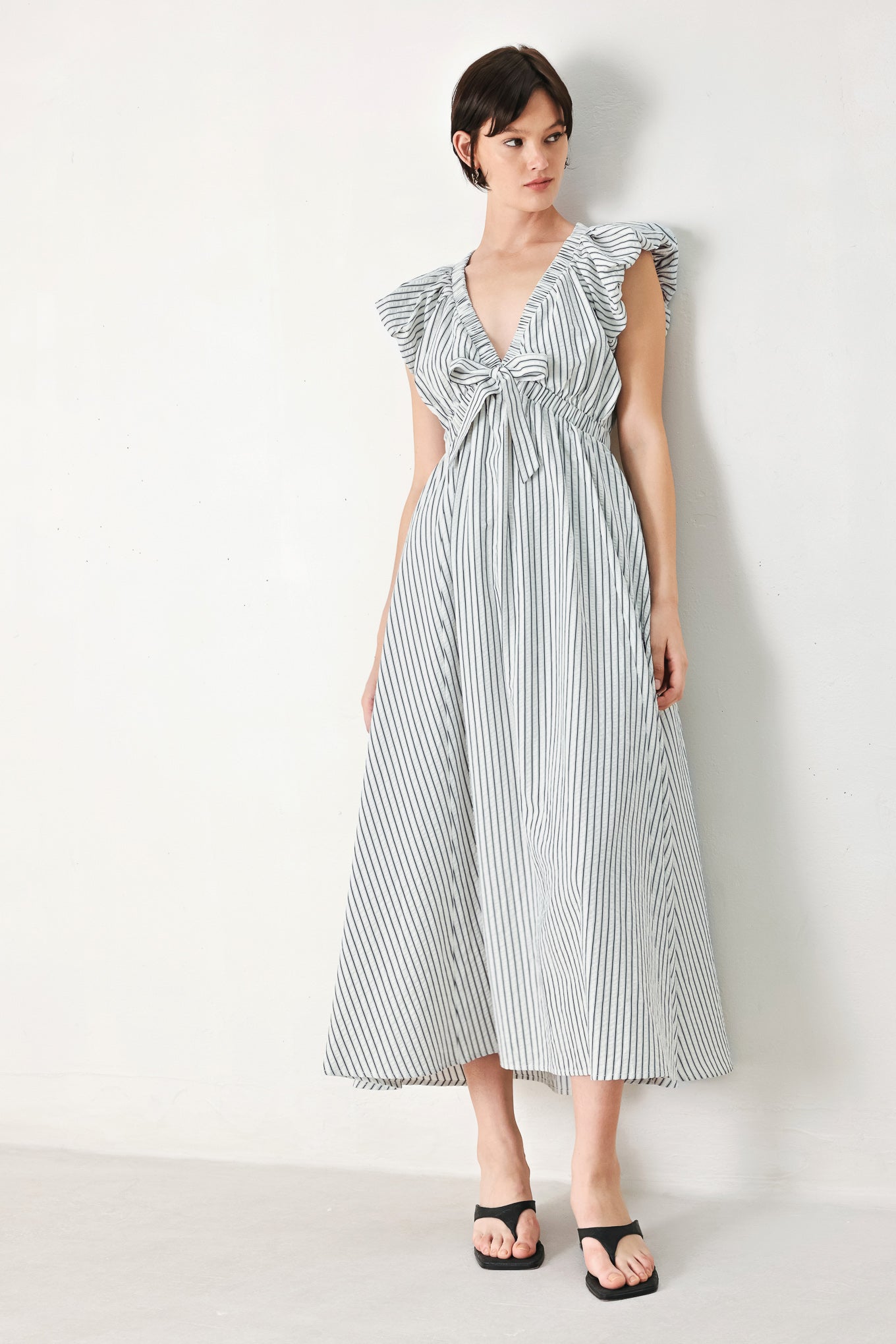 A striped woven midi dress featuring V neckline, short balloon sleeves, front tie, elastic at empire and full skirt