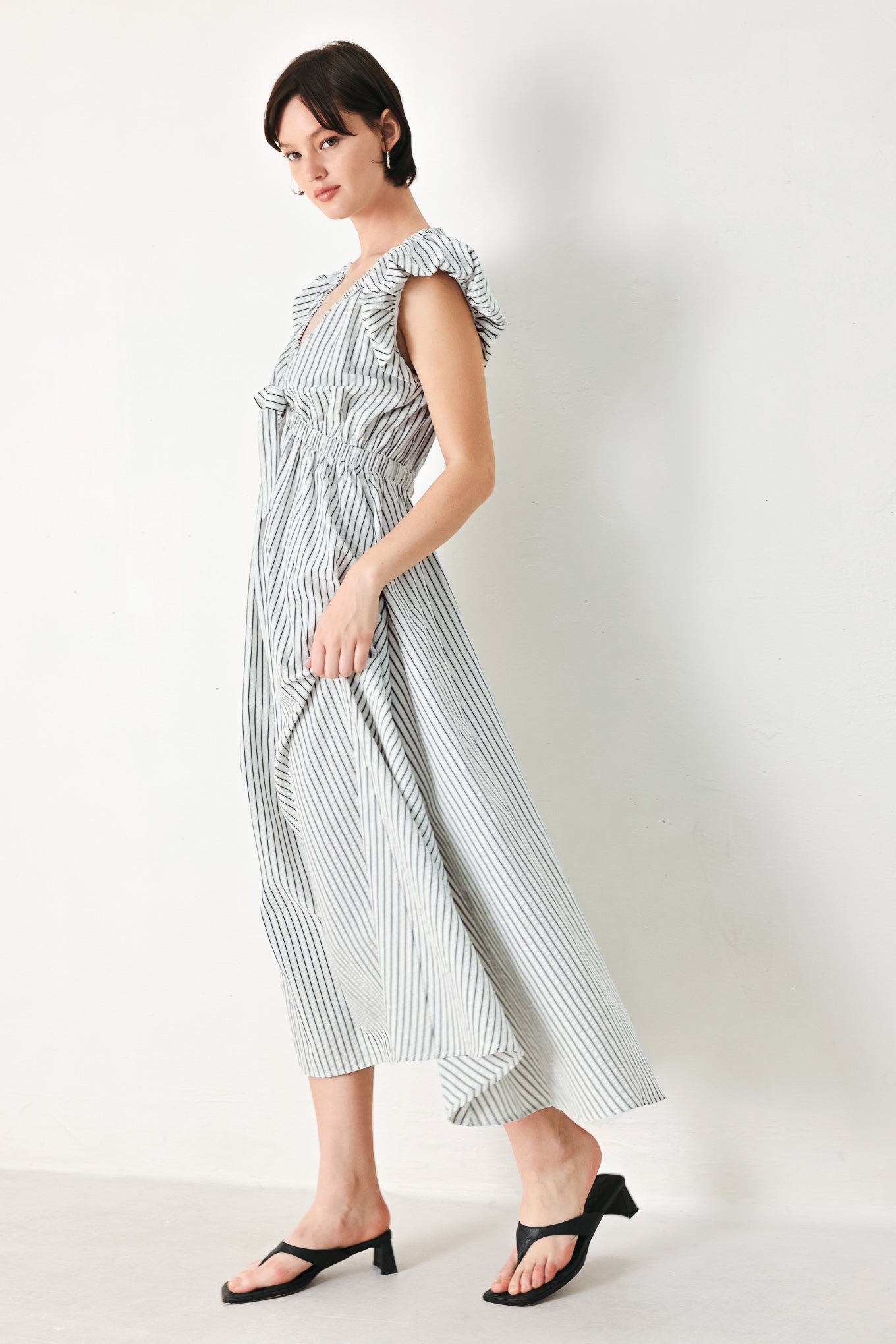 A striped woven midi dress featuring V neckline, short balloon sleeves, front tie, elastic at empire and full skirt
