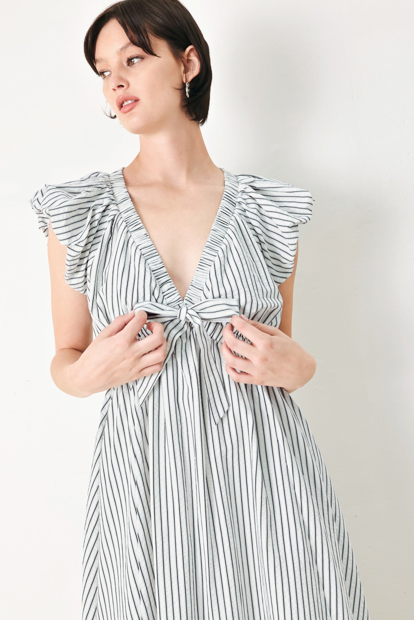 A striped woven midi dress featuring V neckline, short balloon sleeves, front tie, elastic at empire and full skirt