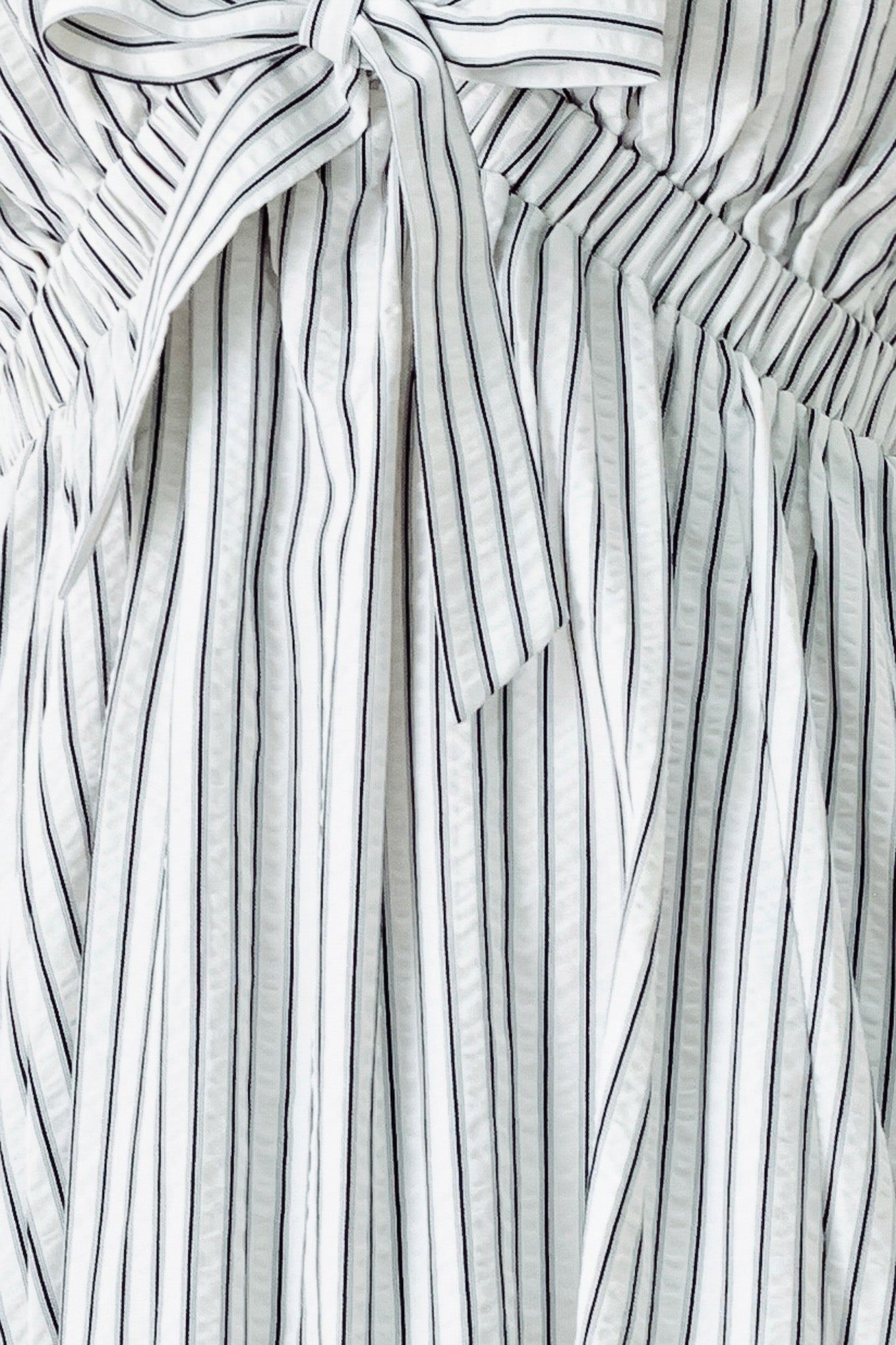 A striped woven midi dress featuring V neckline, short balloon sleeves, front tie, elastic at empire and full skirt