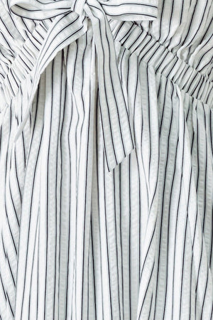 A striped woven midi dress featuring V neckline, short balloon sleeves, front tie, elastic at empire and full skirt