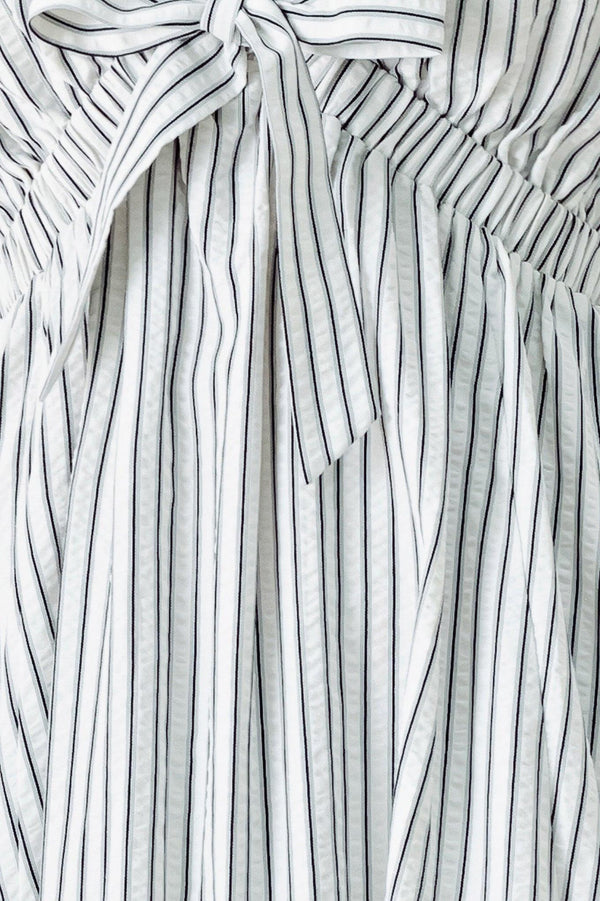 A striped woven midi dress featuring V neckline, short balloon sleeves, front tie, elastic at empire and full skirt