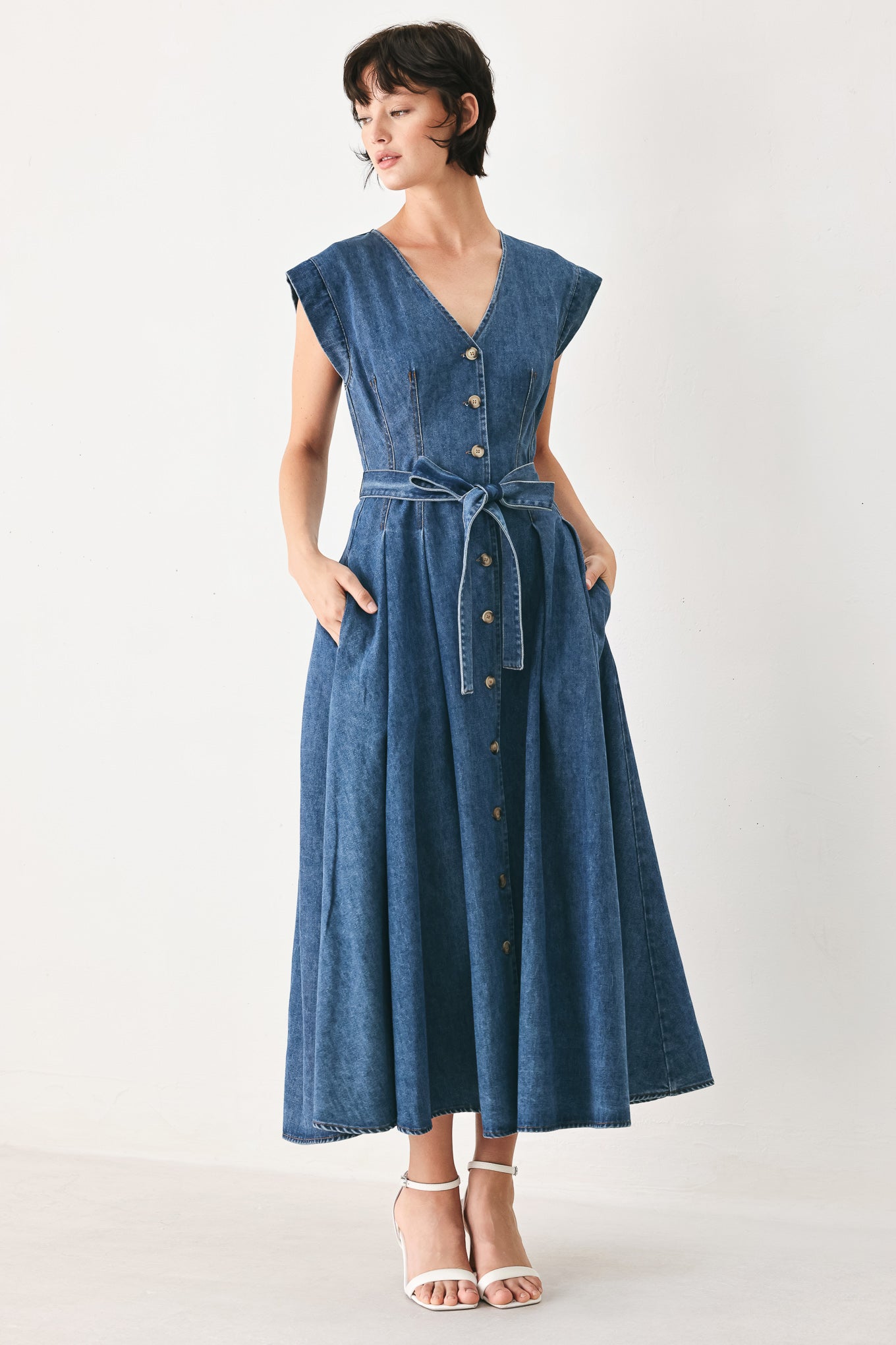 Woman wearing a short sleeve blue denim midi dress with V neckline, front button down, corset waist, self sash tie and full skirt | FREEMARKET