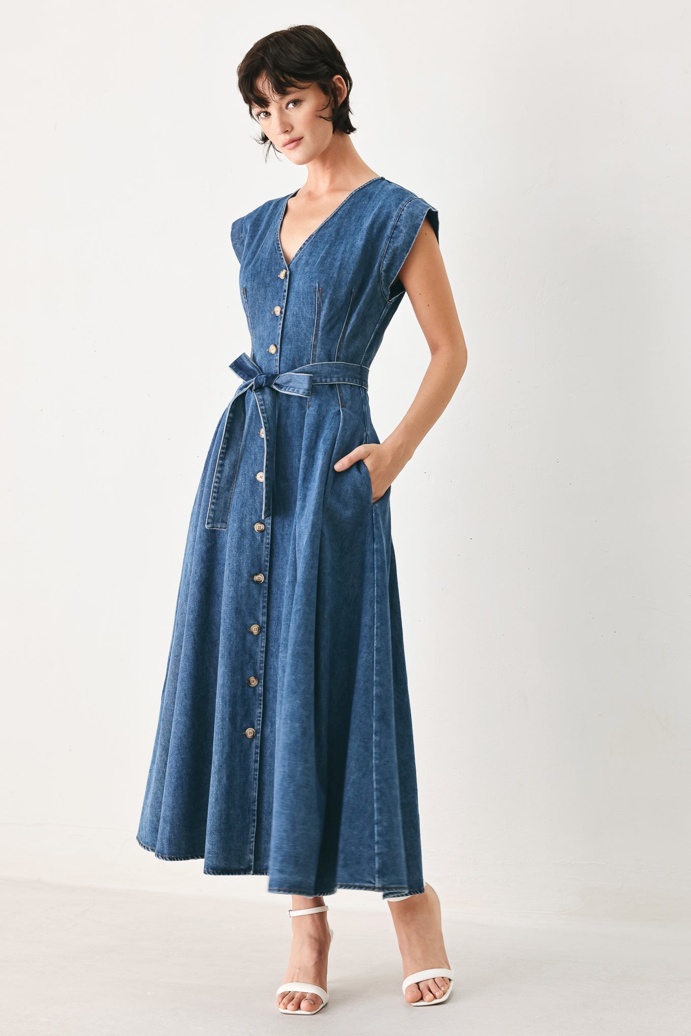 Woman wearing a short sleeve blue denim midi dress with V neckline, front button down, corset waist, self sash tie and full skirt | FREEMARKET