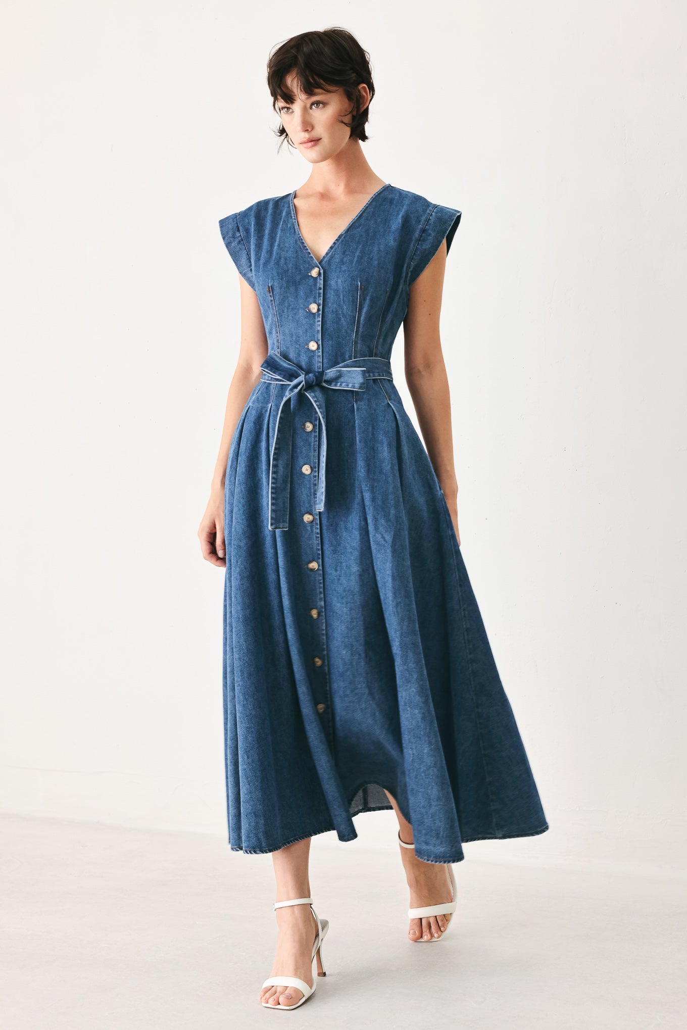 Woman wearing a short sleeve blue denim midi dress with V neckline, front button down, corset waist, self sash tie and full skirt | FREEMARKET