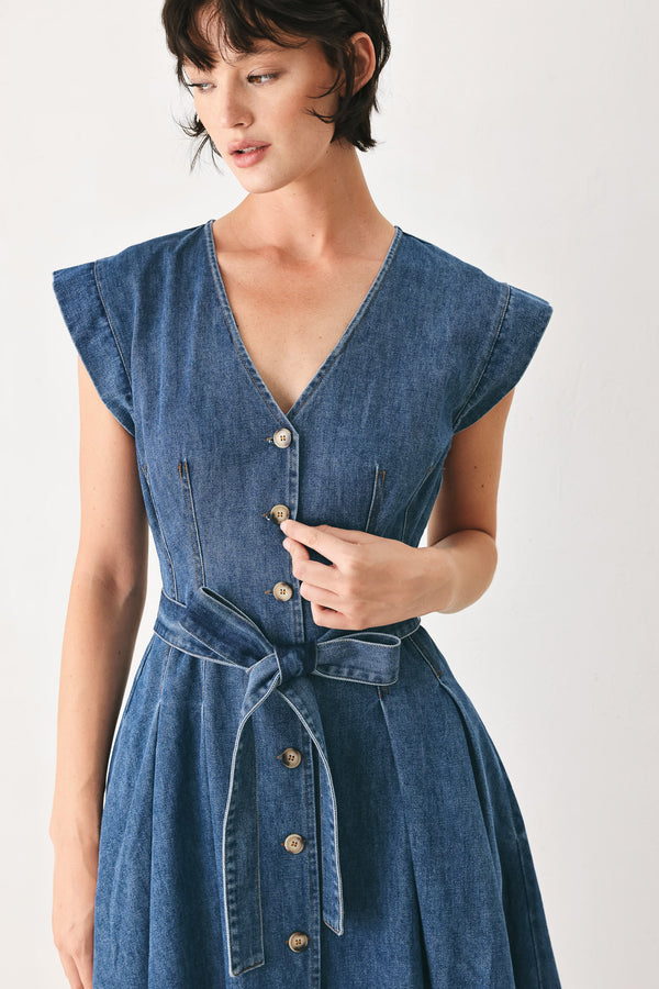 Woman wearing a short sleeve blue denim midi dress with V neckline, front button down, corset waist, self sash tie and full skirt | FREEMARKET
