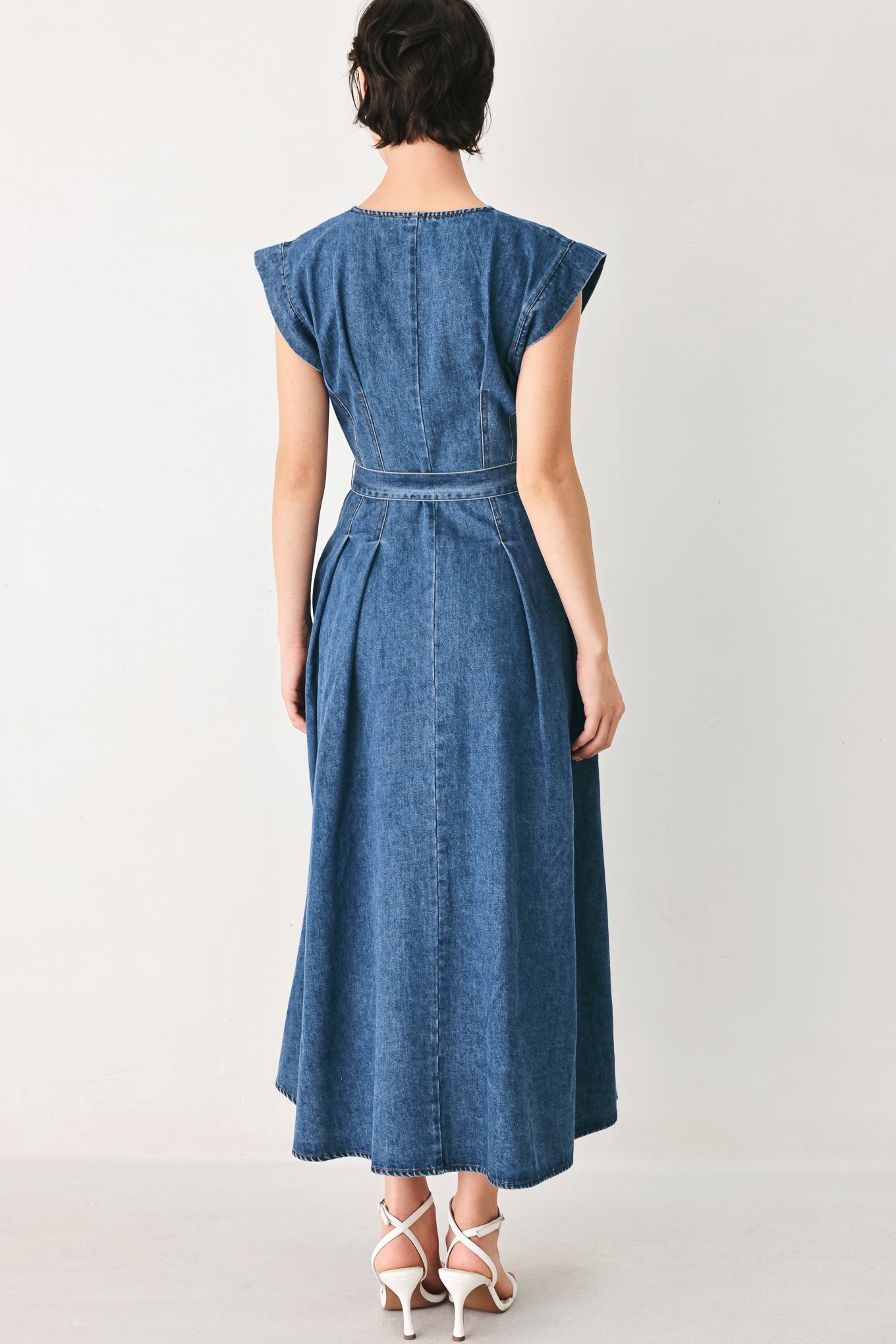 Woman wearing a short sleeve blue denim midi dress with V neckline, front button down, corset waist, self sash tie and full skirt | FREEMARKET