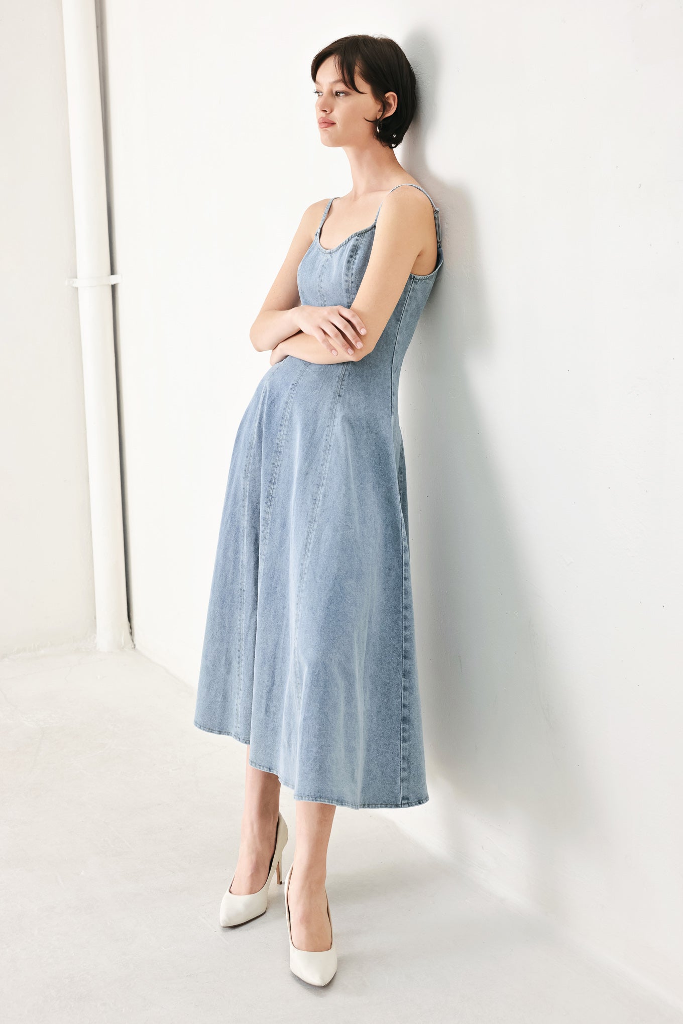 A washed denim midi dress with U neckline, straps, circle skirt and back zipper closure