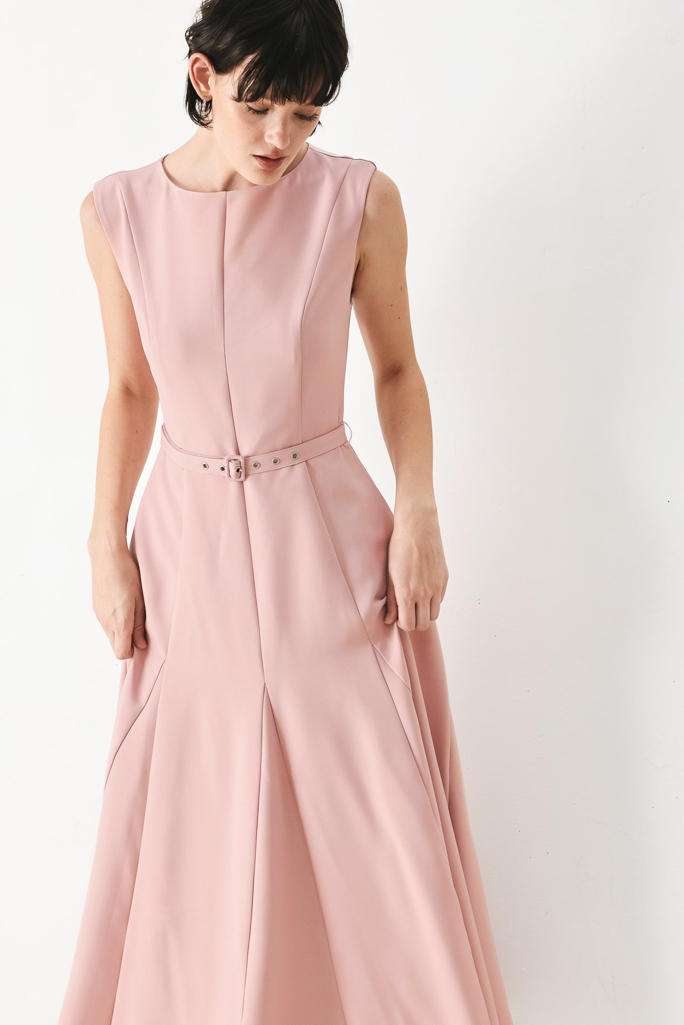 Woman wearing a pink midi dress featuring round neckline, sleeveless, self belt, full circle skirt and back zipper closure | FREEMARKET