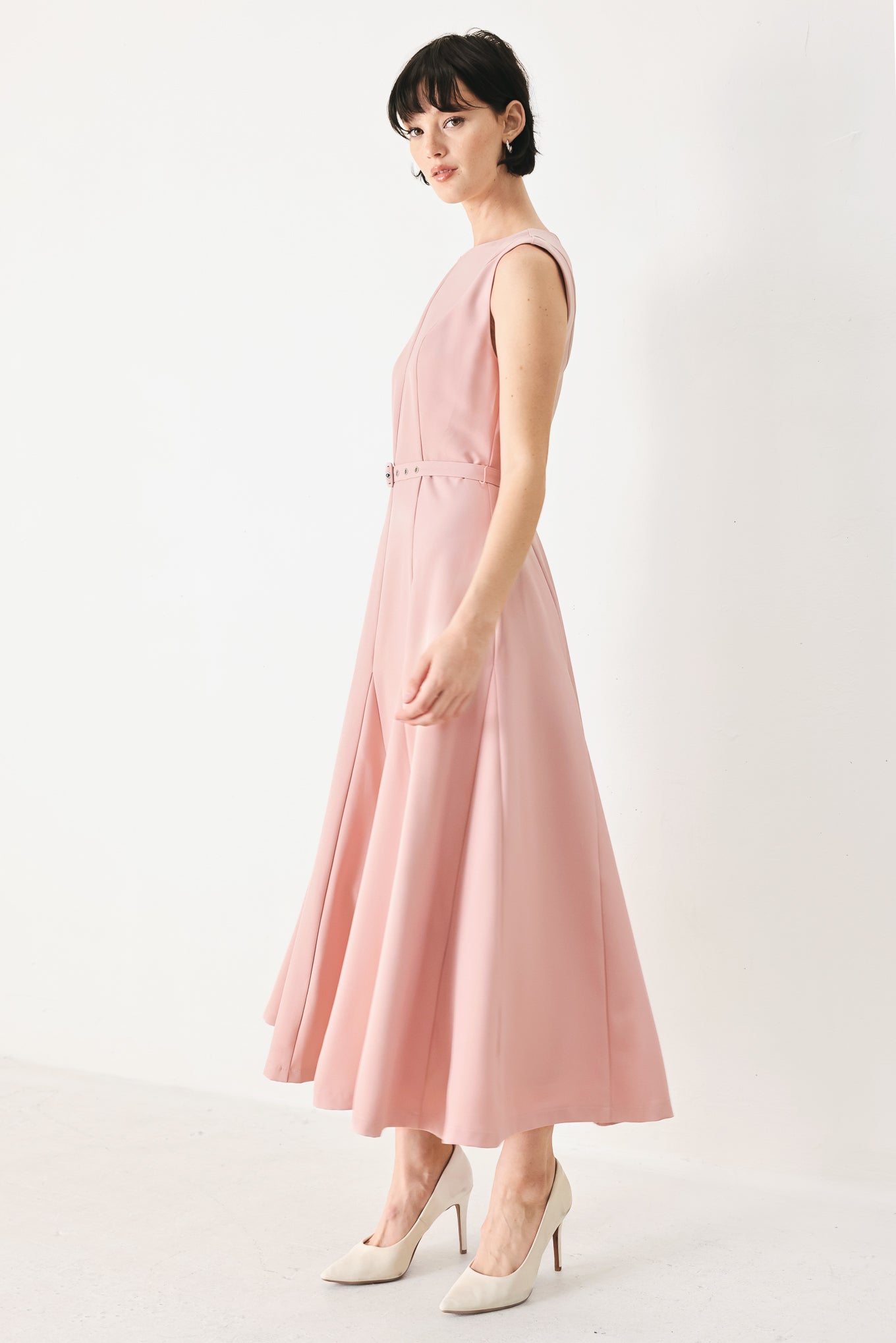 Woman wearing a pink midi dress featuring round neckline, sleeveless, self belt, full circle skirt and back zipper closure | FREEMARKET