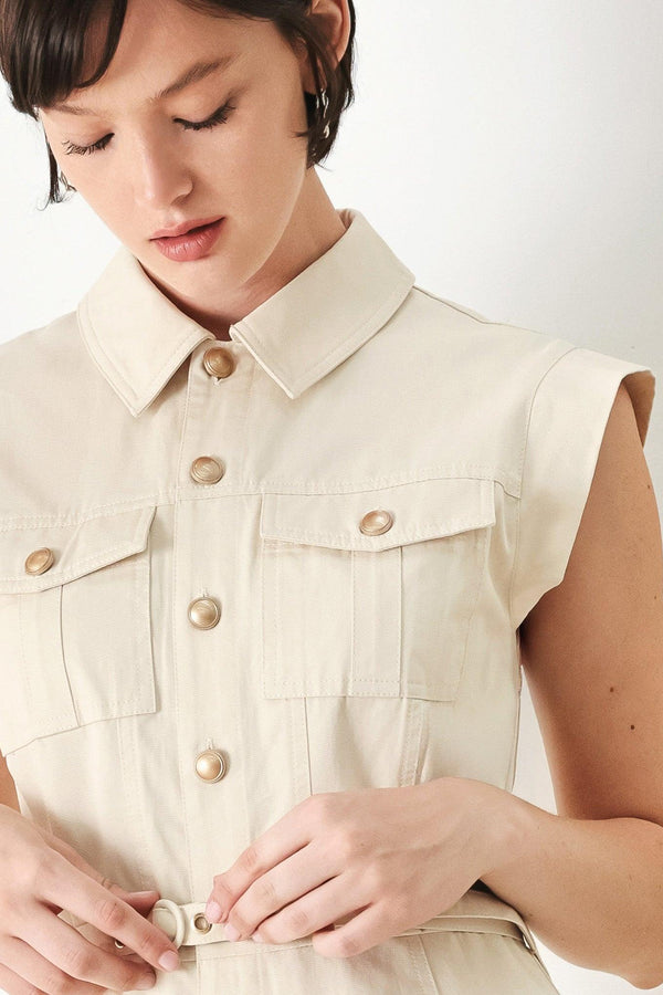 Woman wearing a beige sleeveless dress with button details on a white background | FREEMARKET | Flying Tomato