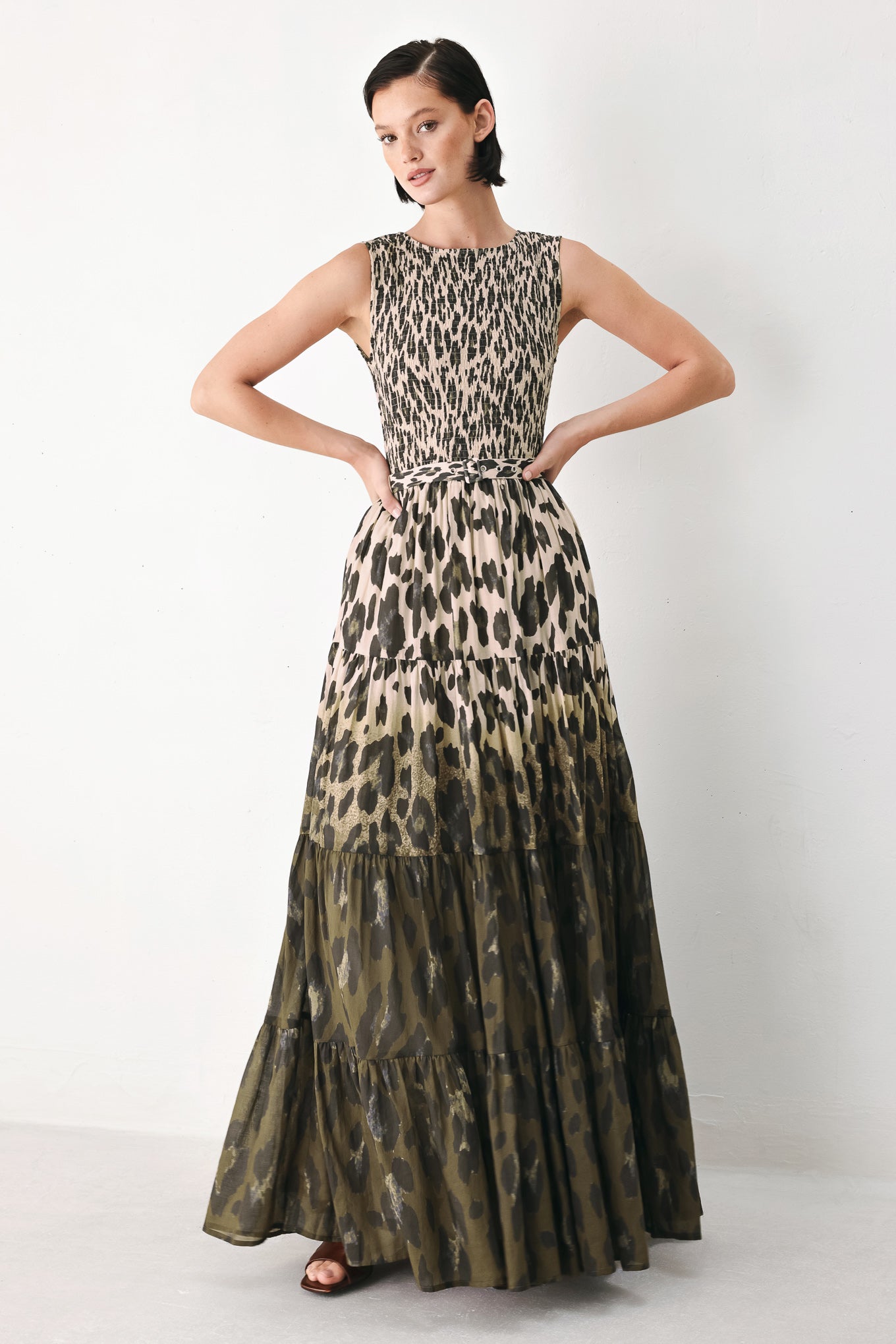 A woman modeling a sleeveless tiered maxi dress with an abstract leopard print in beige & brown | FREEMARKET