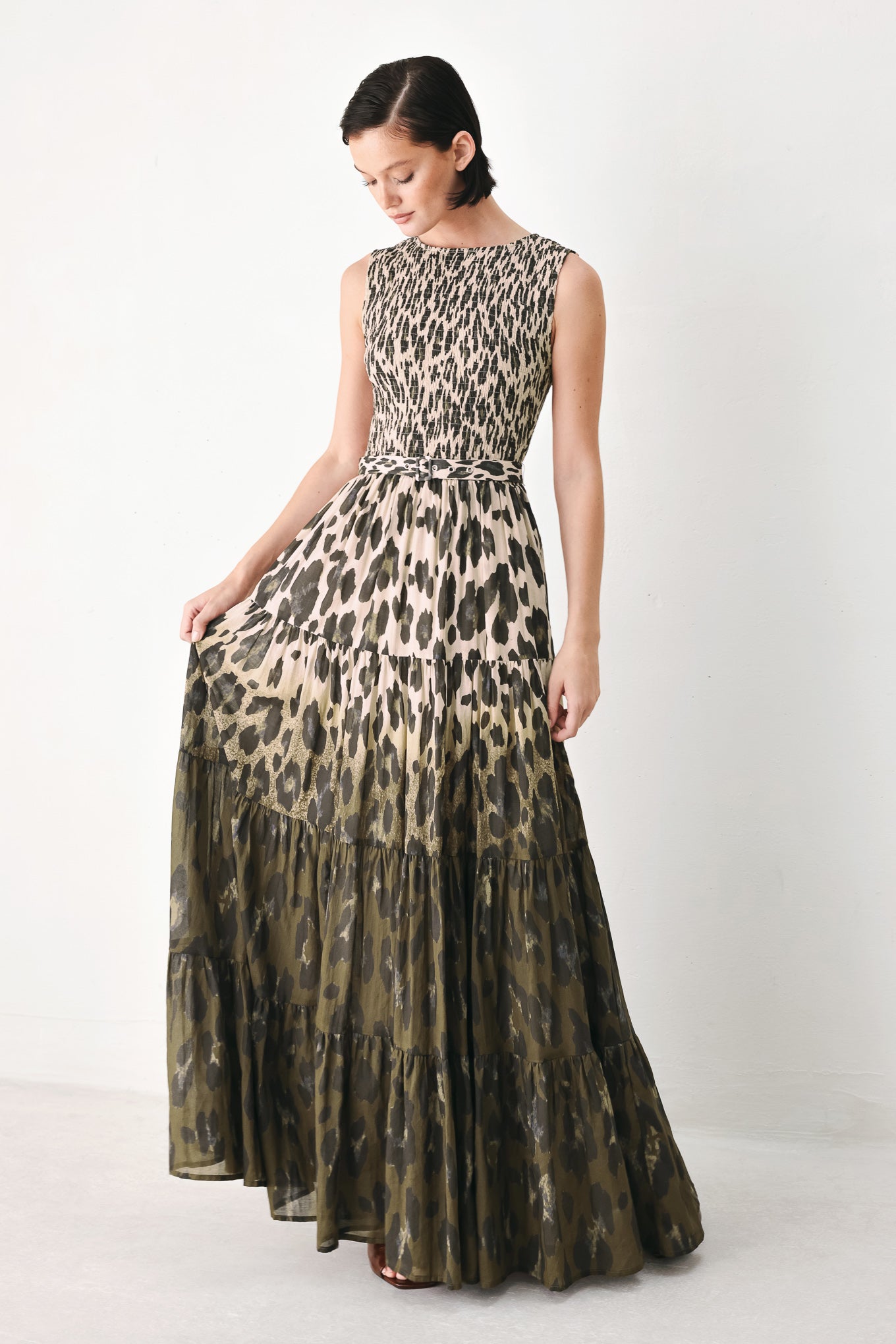 A woman modeling a sleeveless tiered maxi dress with an abstract leopard print in beige & brown | FREEMARKET