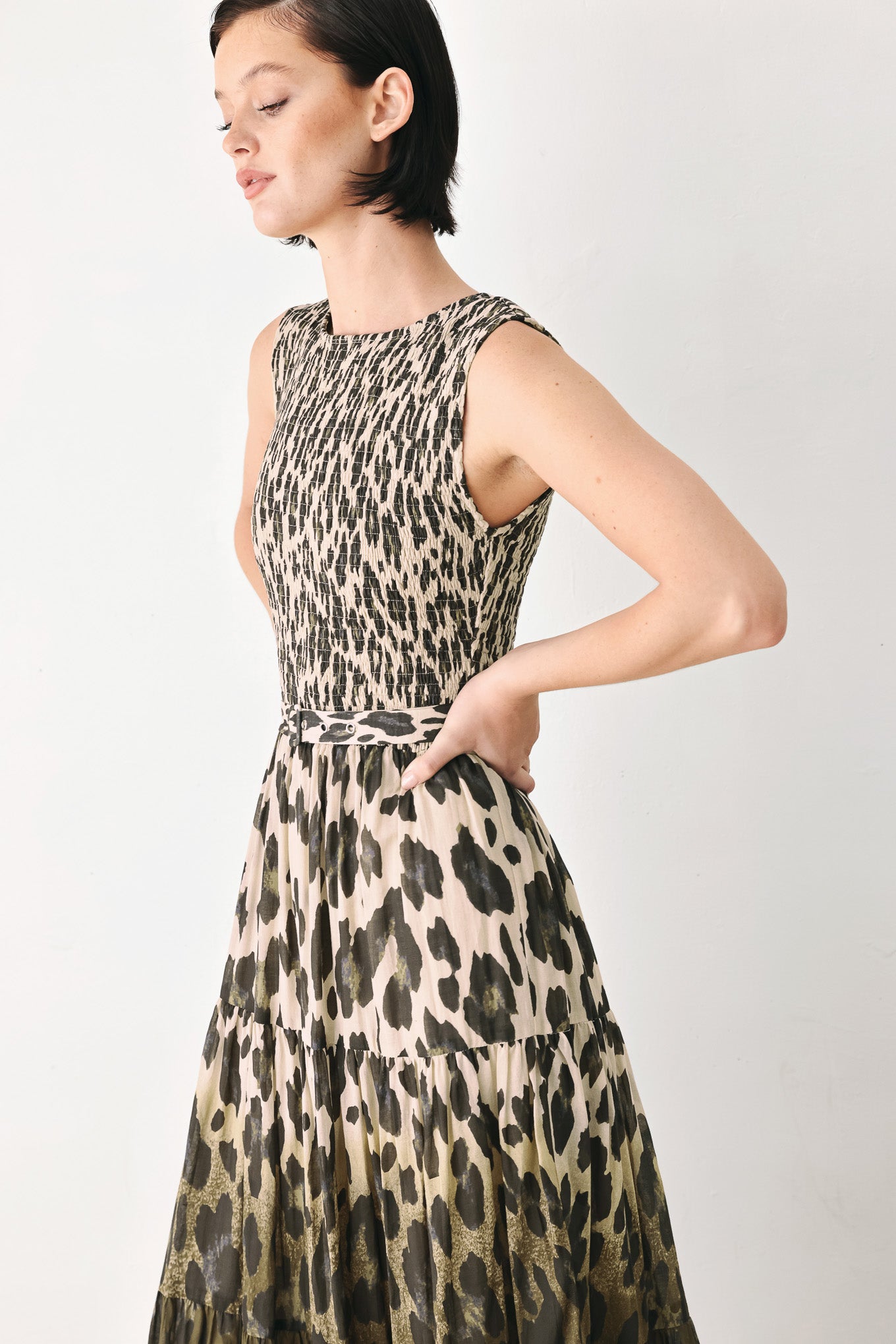 A woman modeling a sleeveless tiered maxi dress with an abstract leopard print in beige & brown | FREEMARKET