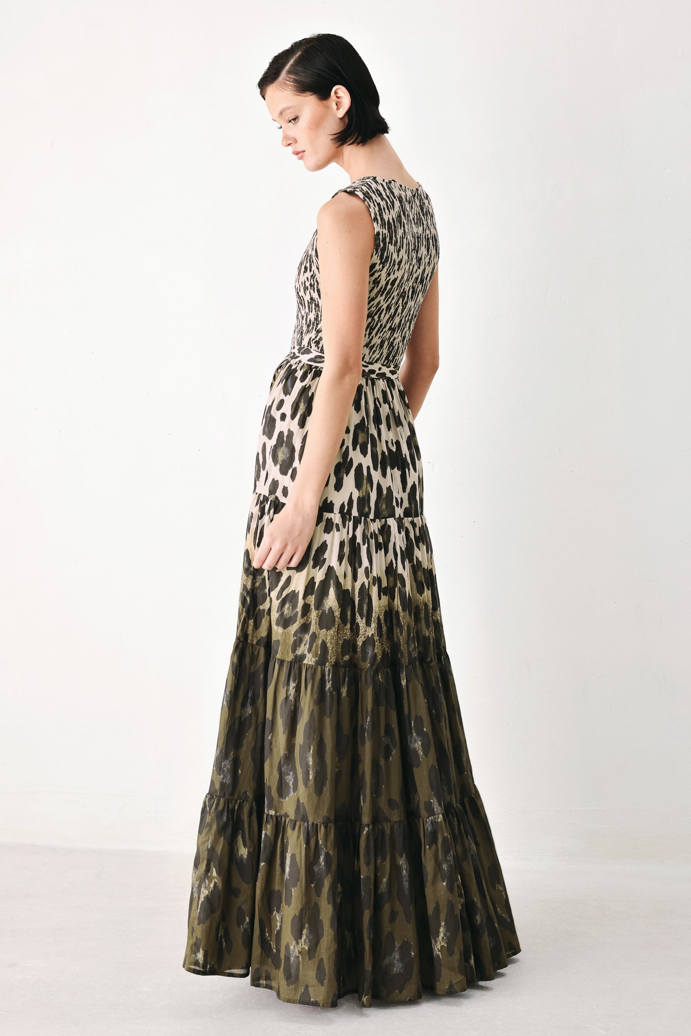 A woman modeling a sleeveless tiered maxi dress with an abstract leopard print in beige & brown | FREEMARKET