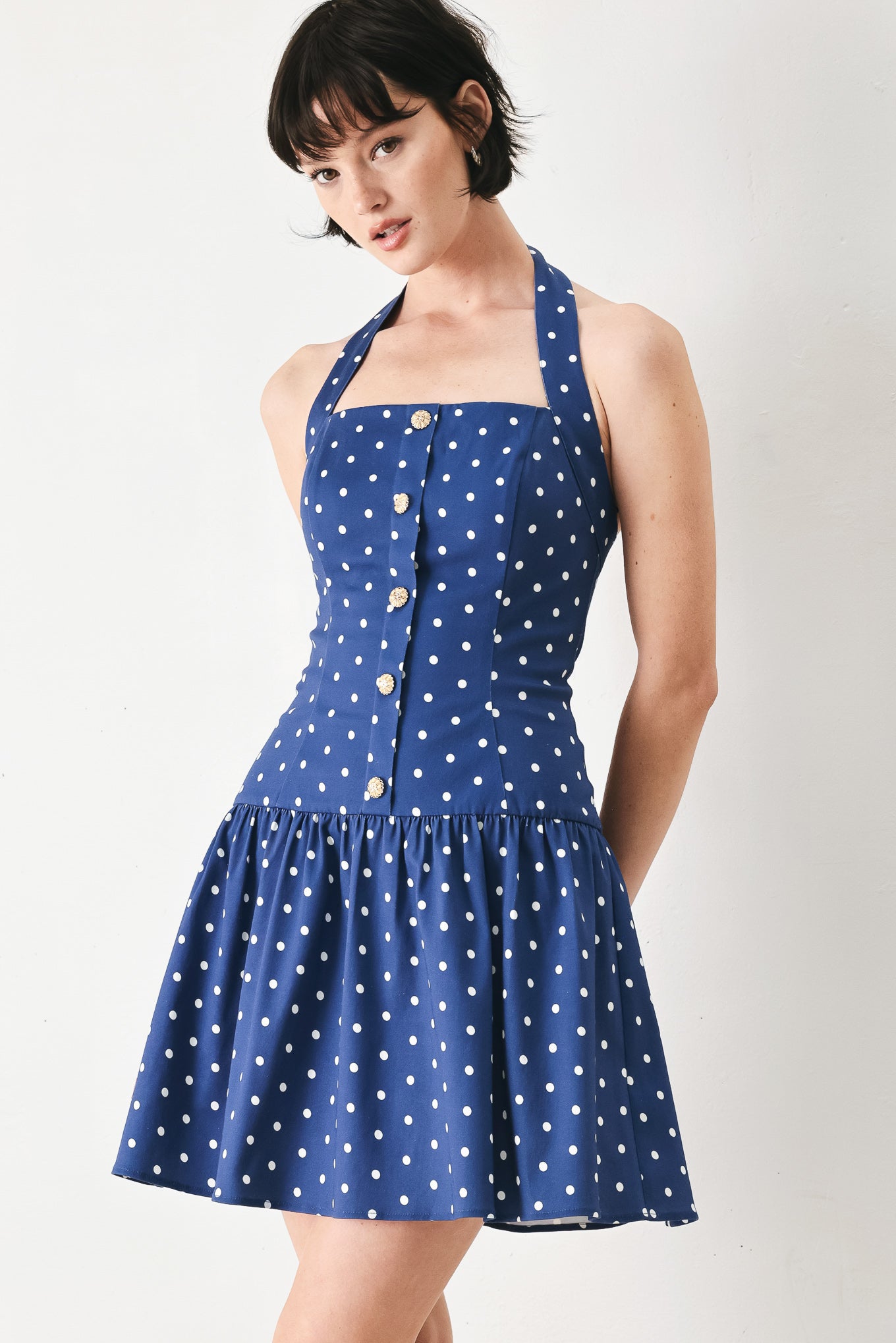 Woman wearing a blue polka dot mini dress featuring straight neckline with halter strap, drop waist and bare back with smocking zipper closure | FREEMARKET