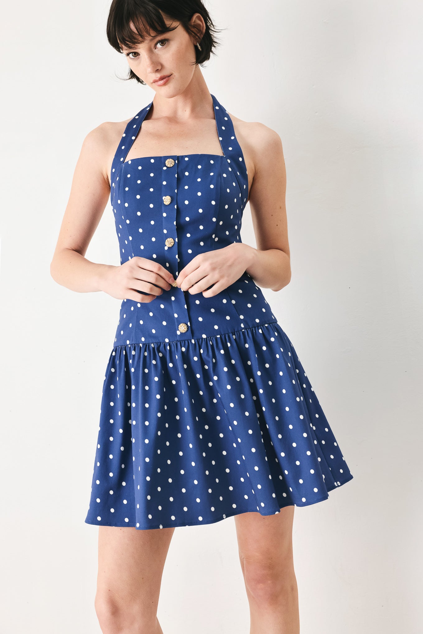 Woman wearing a blue polka dot mini dress featuring straight neckline with halter strap, drop waist and bare back with smocking zipper closure | FREEMARKET