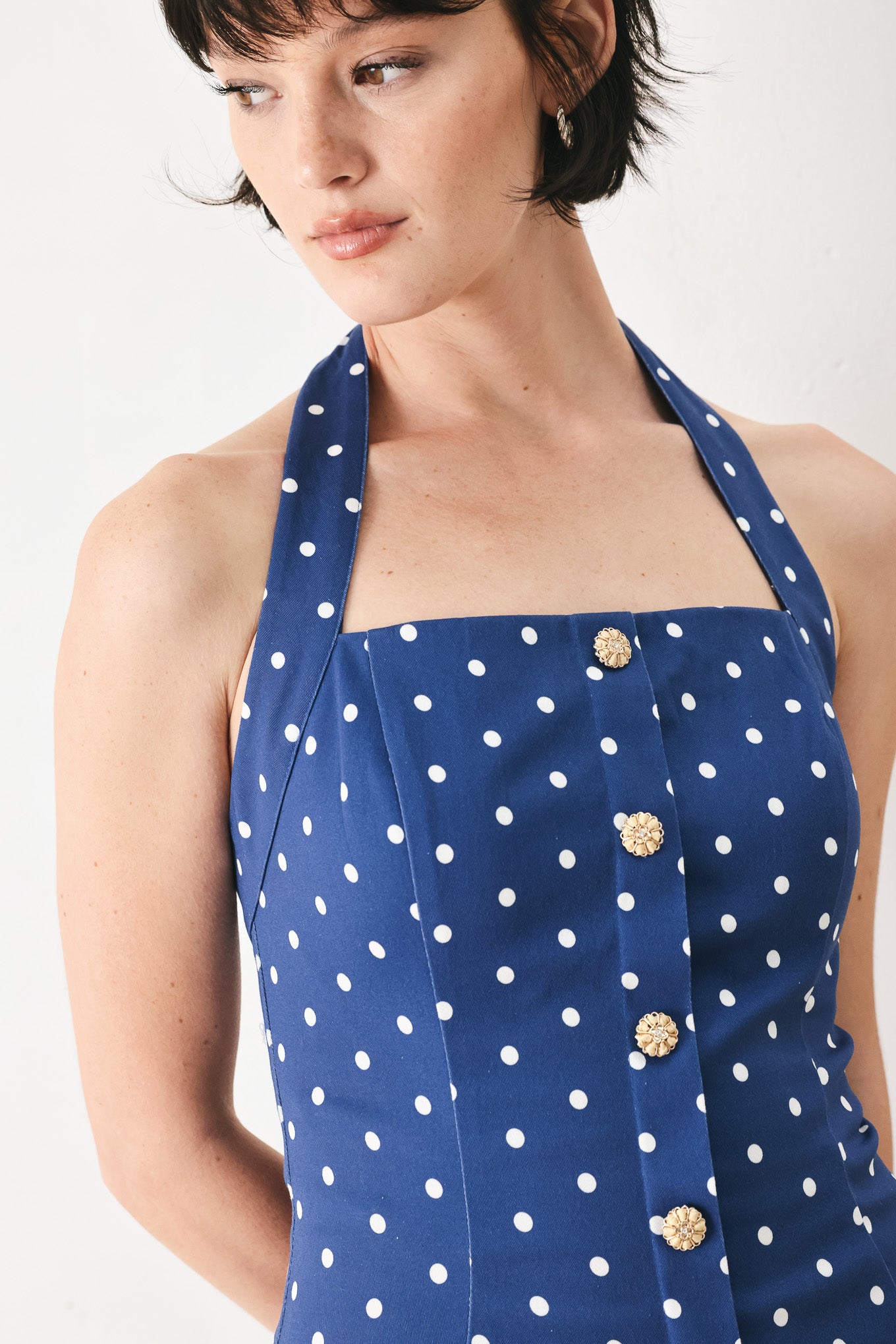 Woman wearing a blue polka dot mini dress featuring straight neckline with halter strap, drop waist and bare back with smocking zipper closure | FREEMARKET