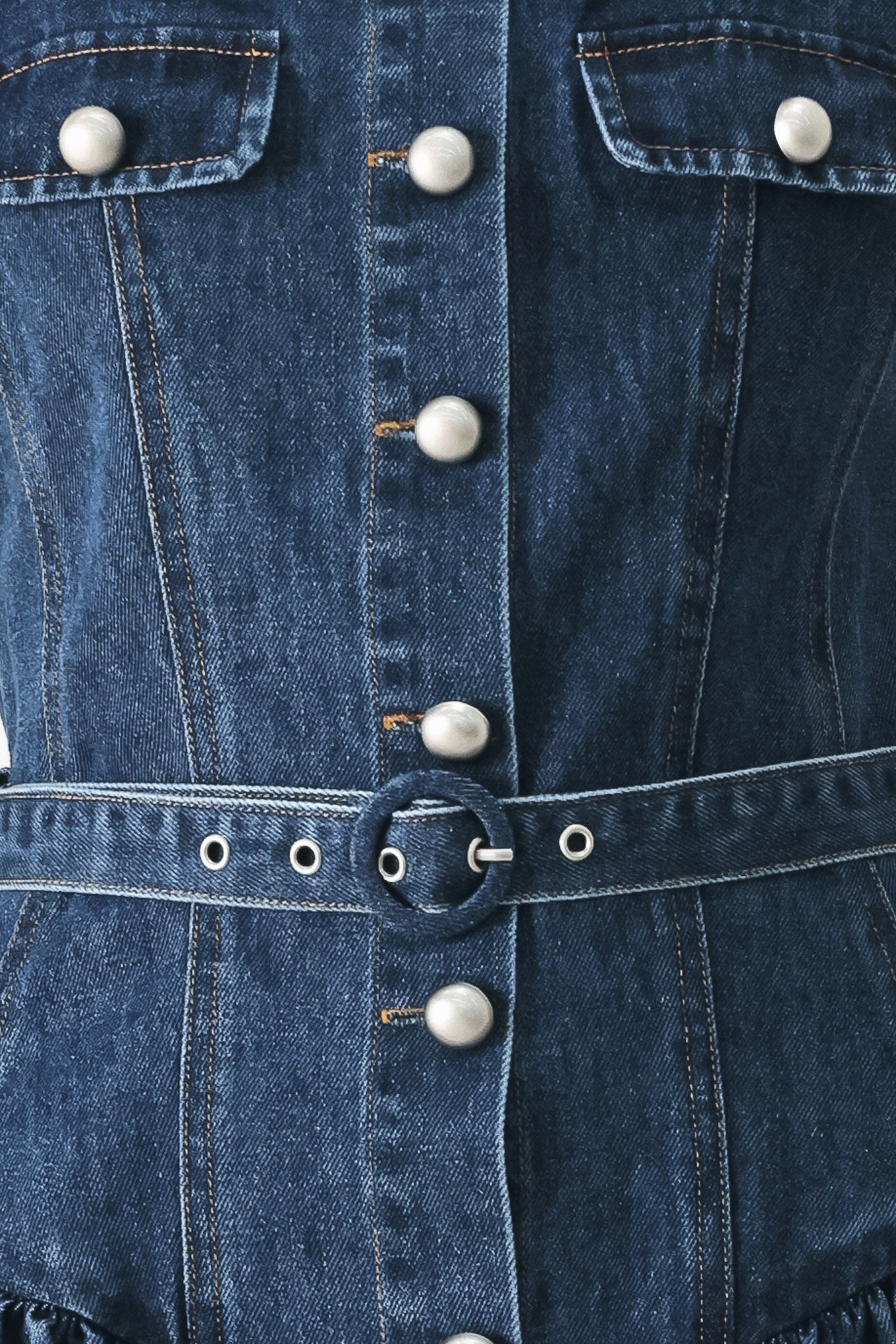 Close up of a blue denim sleeveless mini dress featuring square neckline, front button closure, self belt and side shirred full skirt | FREEMARKET