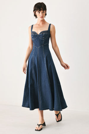 Woman wearing a blue indigo denim midi dress featuring sweetheart neckline, straps, circle skirt and back zipper closure | FREEMARKET