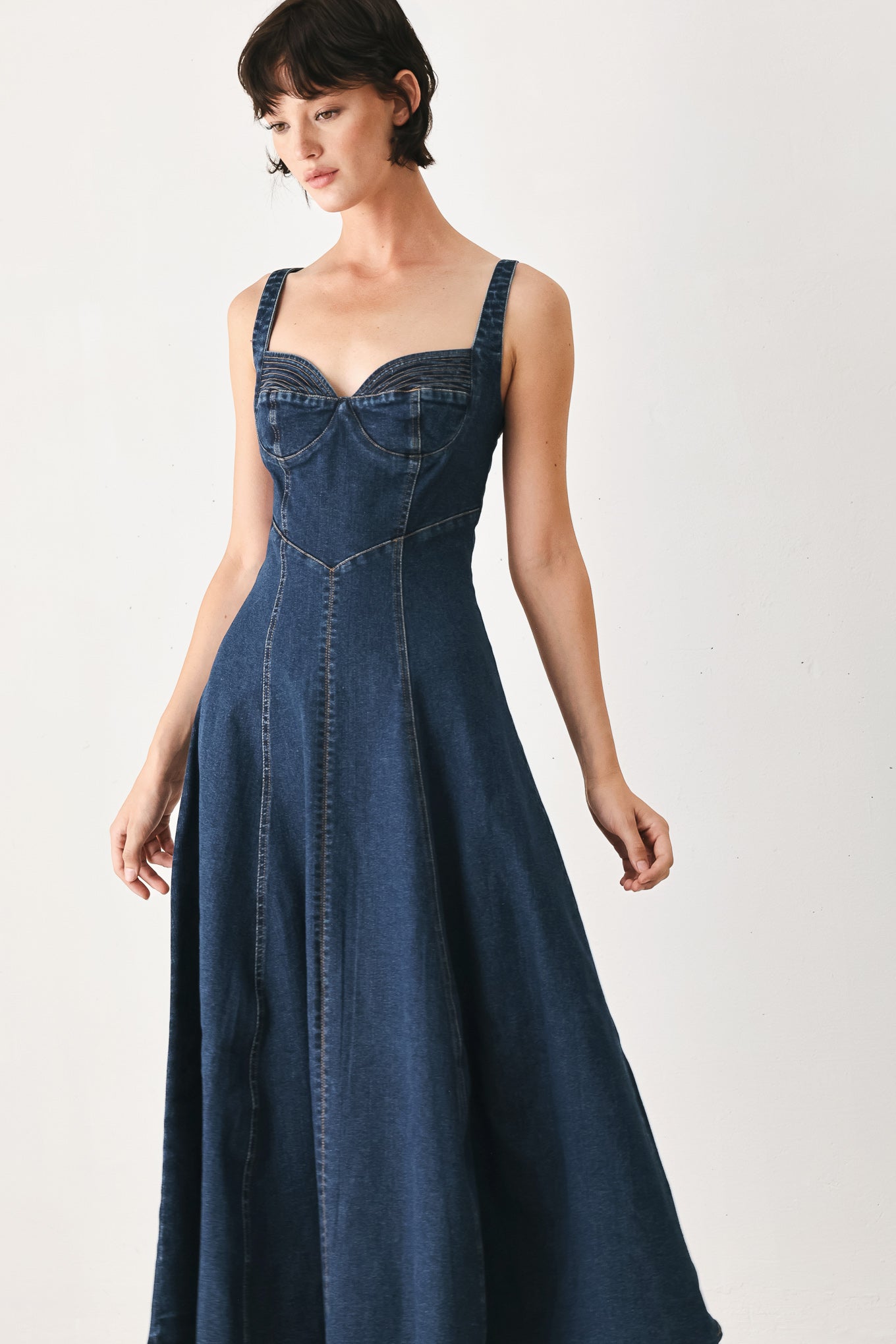 Woman wearing a blue indigo denim midi dress featuring sweetheart neckline, straps, circle skirt and back zipper closure | FREEMARKET