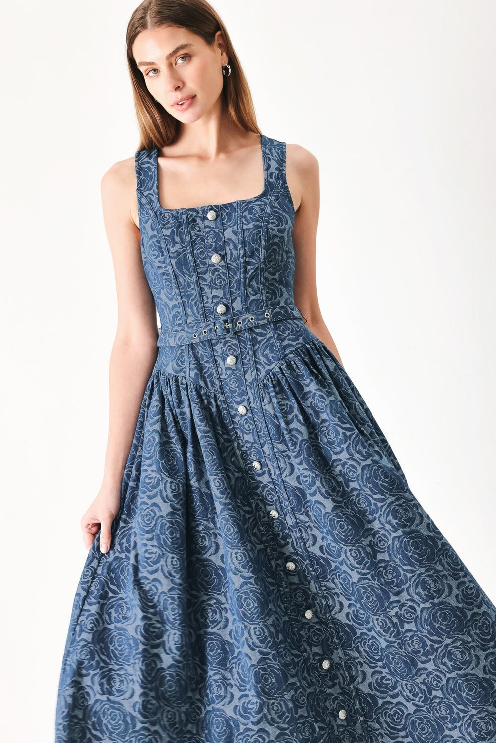 Woman wearing a blue patterned jacquard denim midi dress featuring square neckline, sleeveless, button down detail, self belt, basque waistline, full skirt and back zipper closure | FREEMARKET | Flying Tomato