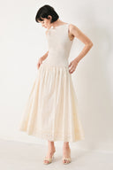 Woman wearing a sleeveless ivory midi dress featuring sweater knit top with round neckline, drop waist, woven eyelet skirt, U back neck and cut out at waist | FREEMARKET