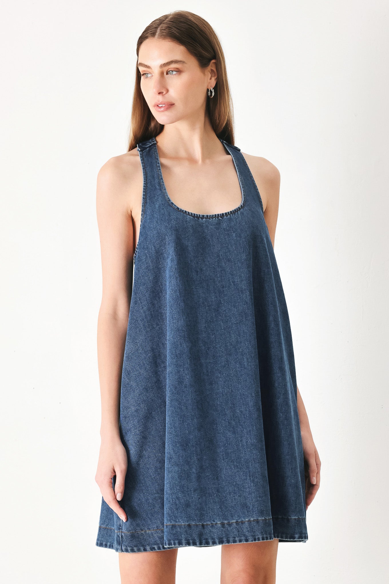 Woman wearing a blue denim mini dress with halter neckline and racer back and buckle | FREEMARKET | Flying Tomato
