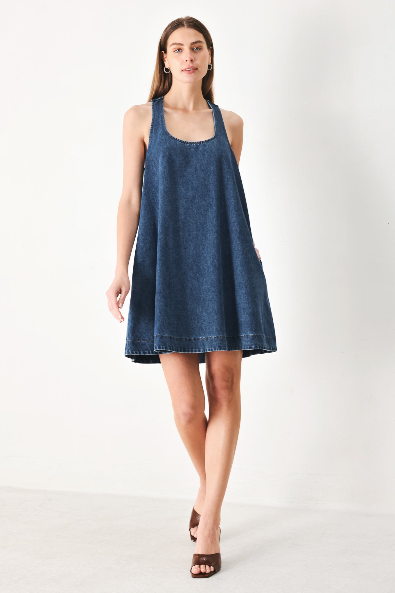 Woman wearing a blue denim mini dress with halter neckline and racer back and buckle | FREEMARKET | Flying Tomato