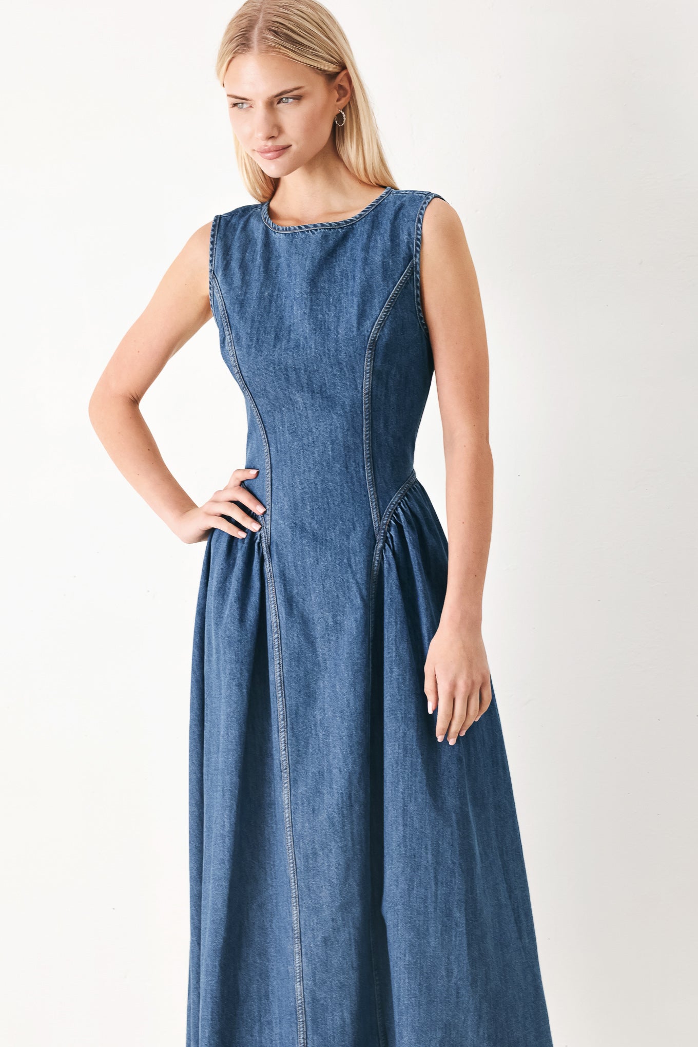 Woman wearing a blue denim midi dress featuring round neckline, sleeveless, side shirred full skirt and back zipper closure | FREEMARKET