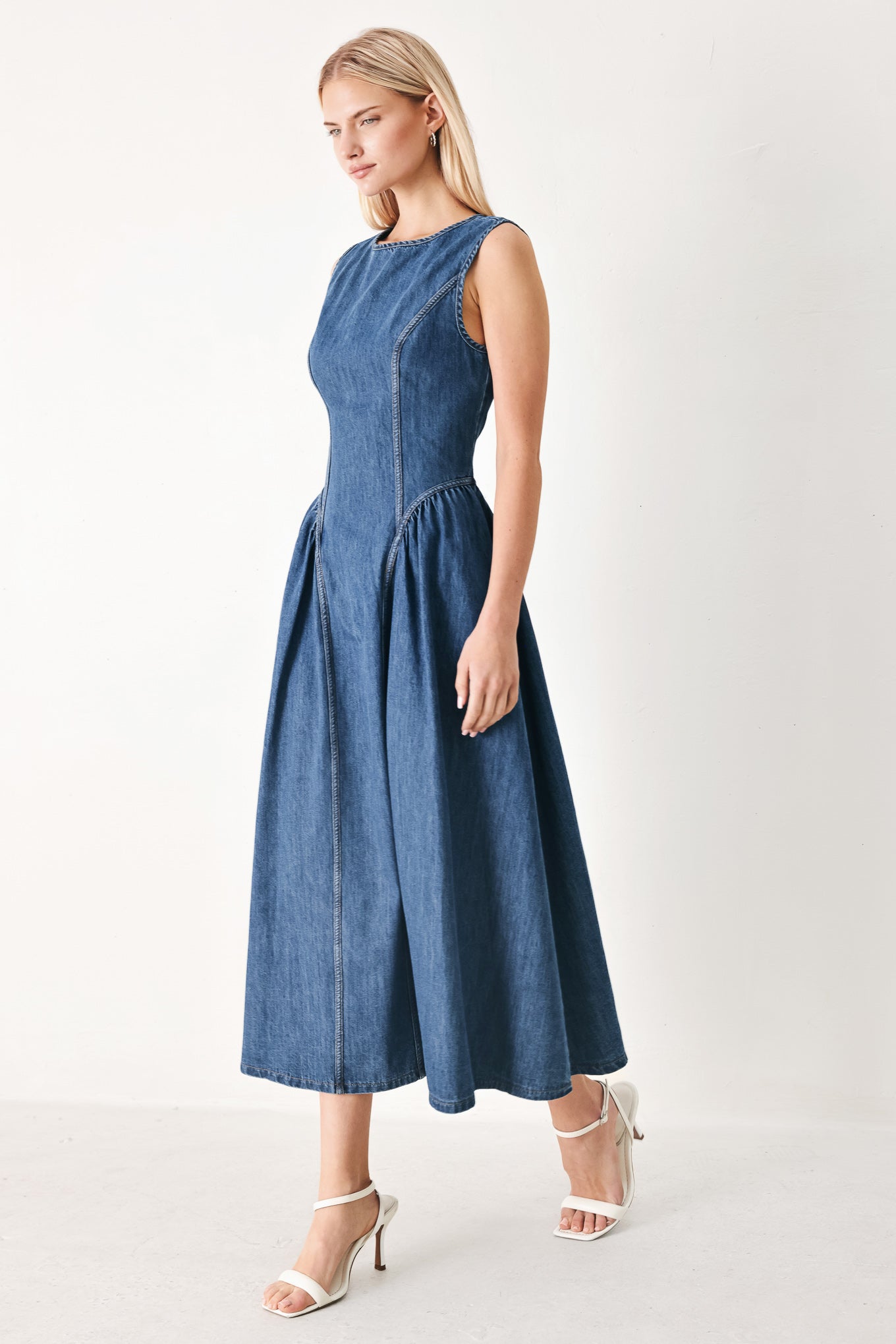 Woman wearing a blue denim midi dress featuring round neckline, sleeveless, side shirred full skirt and back zipper closure | FREEMARKET