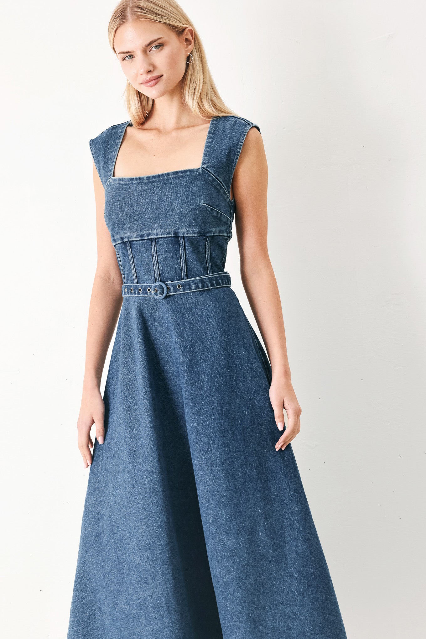 Woman wearing a blue denim midi dress featuring square neckline, corset waist, self belt, side pockets and back zipper closure | FREEMARKET