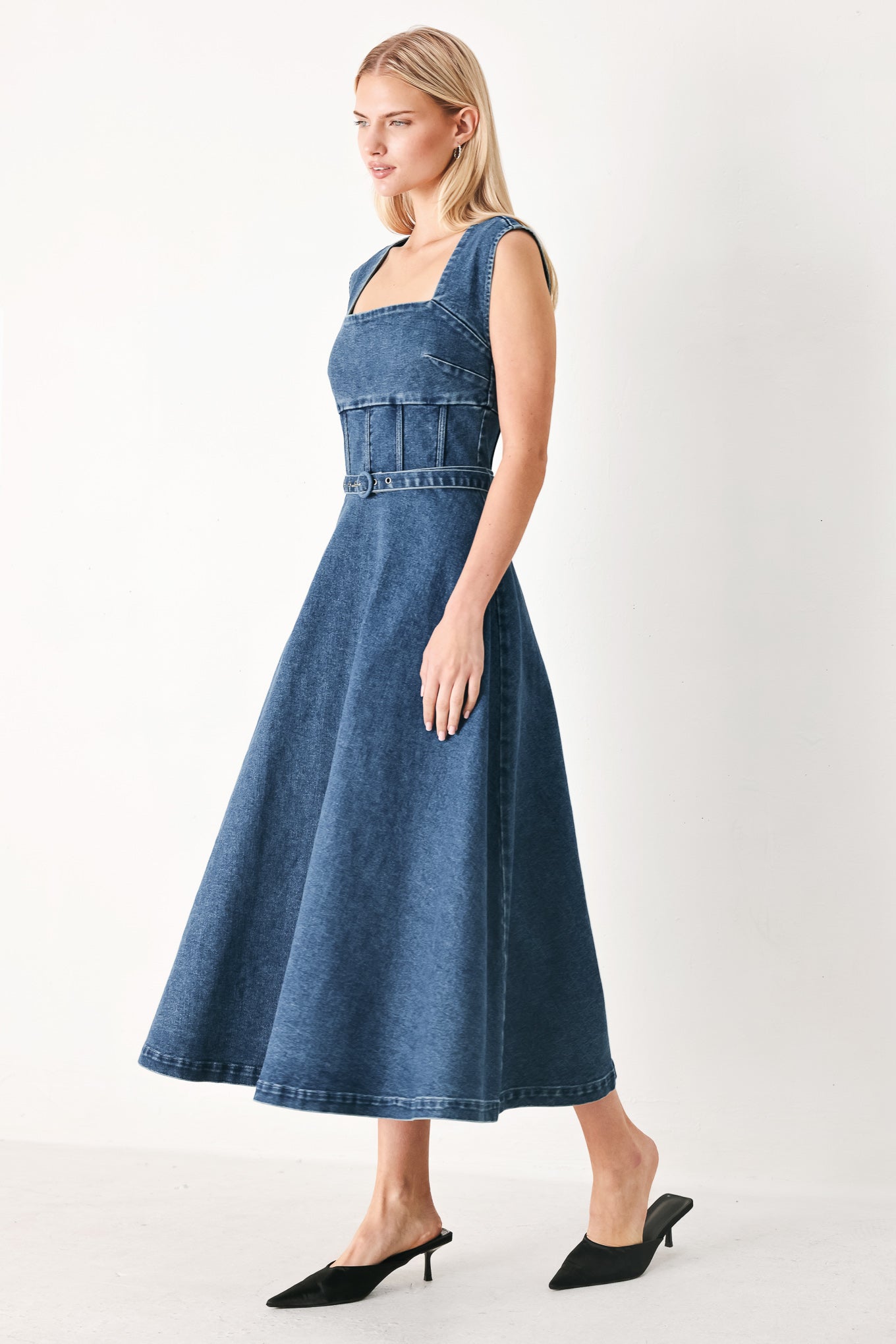 Woman wearing a blue denim midi dress featuring square neckline, corset waist, self belt, side pockets and back zipper closure | FREEMARKET
