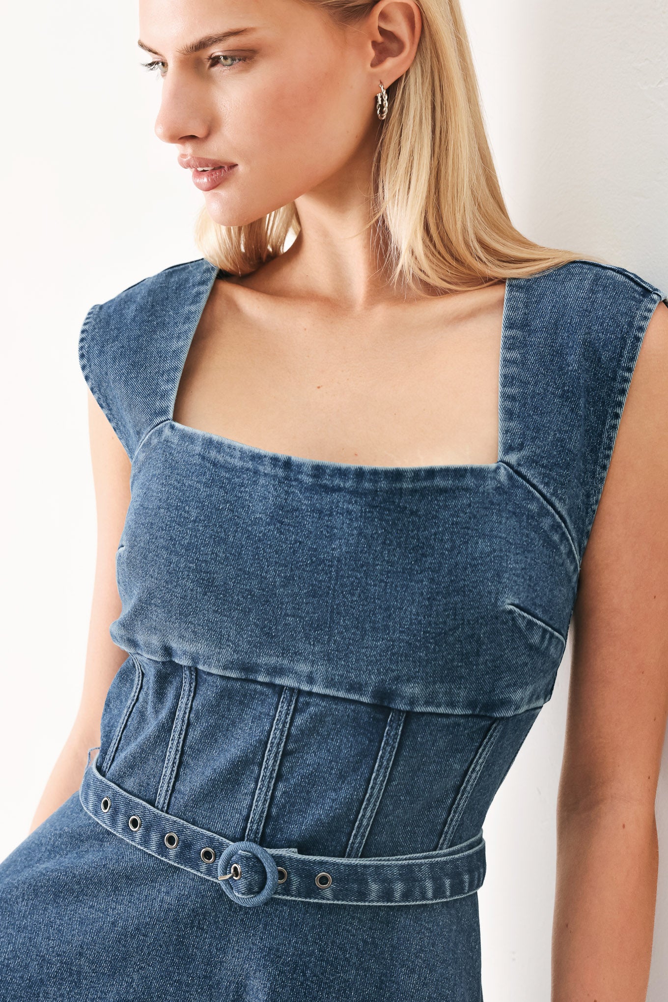 Woman wearing a blue denim midi dress featuring square neckline, corset waist, self belt, side pockets and back zipper closure | FREEMARKET